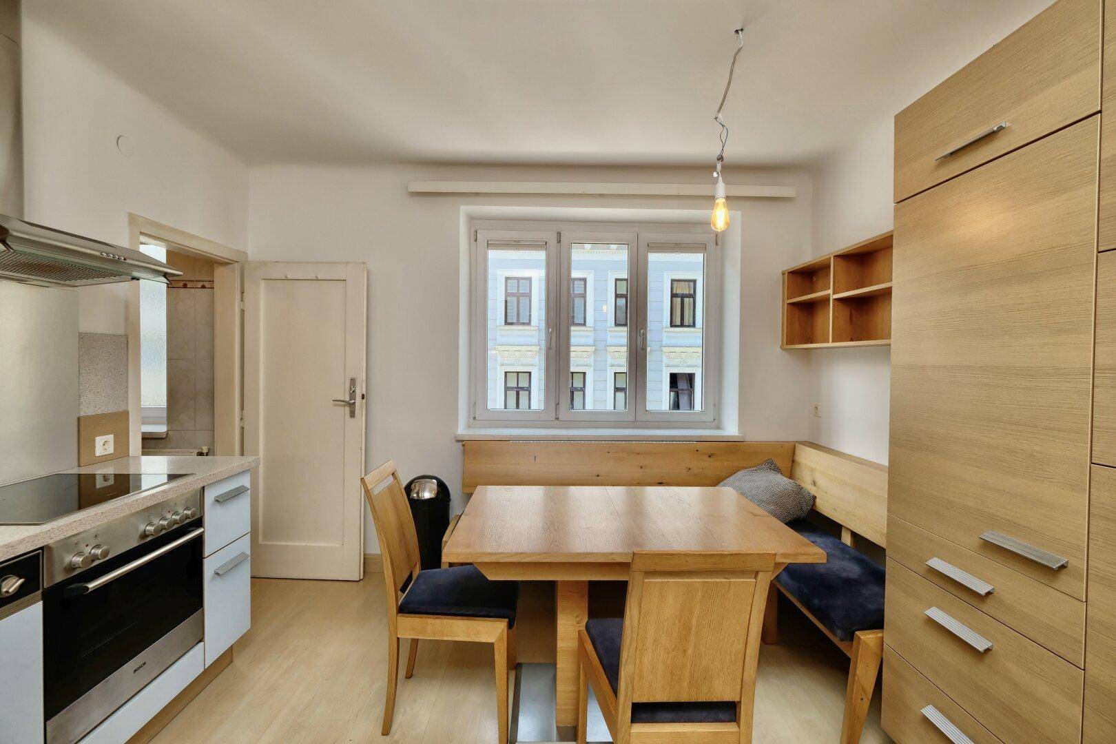 Funktionale Küche mit Essbereich, Holzbänken und Fensterblick auf die Umgebung.