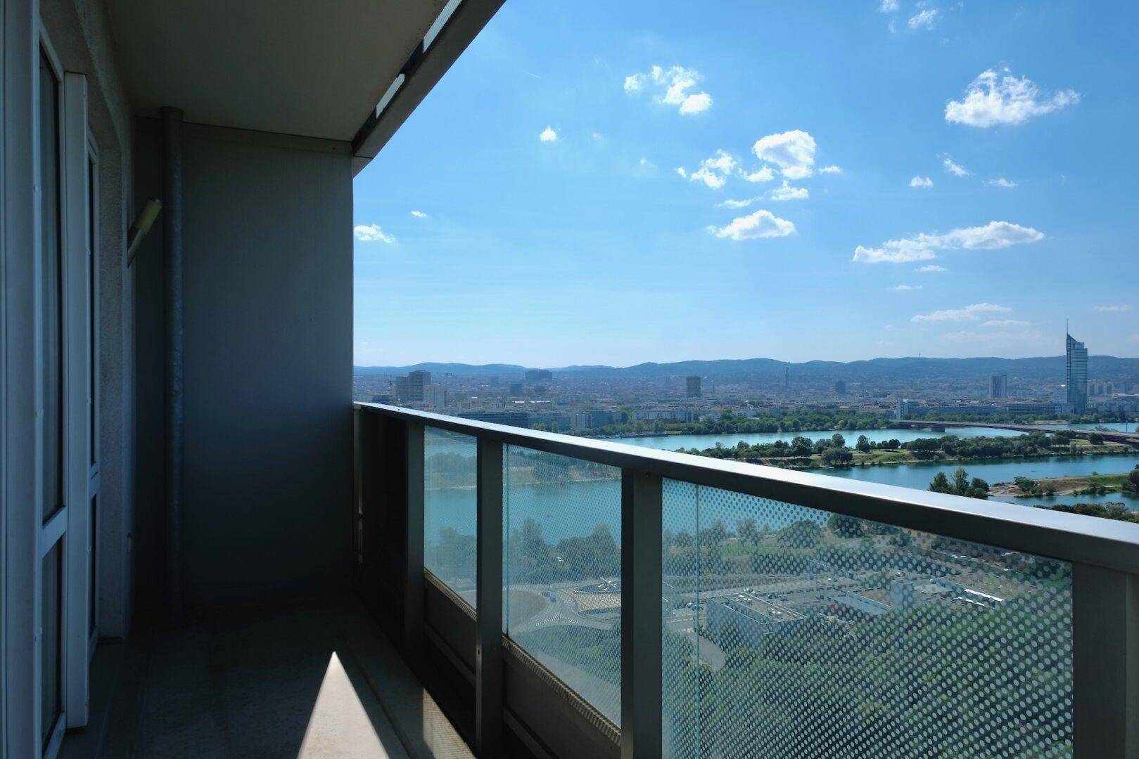 Balkon mit Glasgeländer und weitem Blick über die Stadt und die Donau.