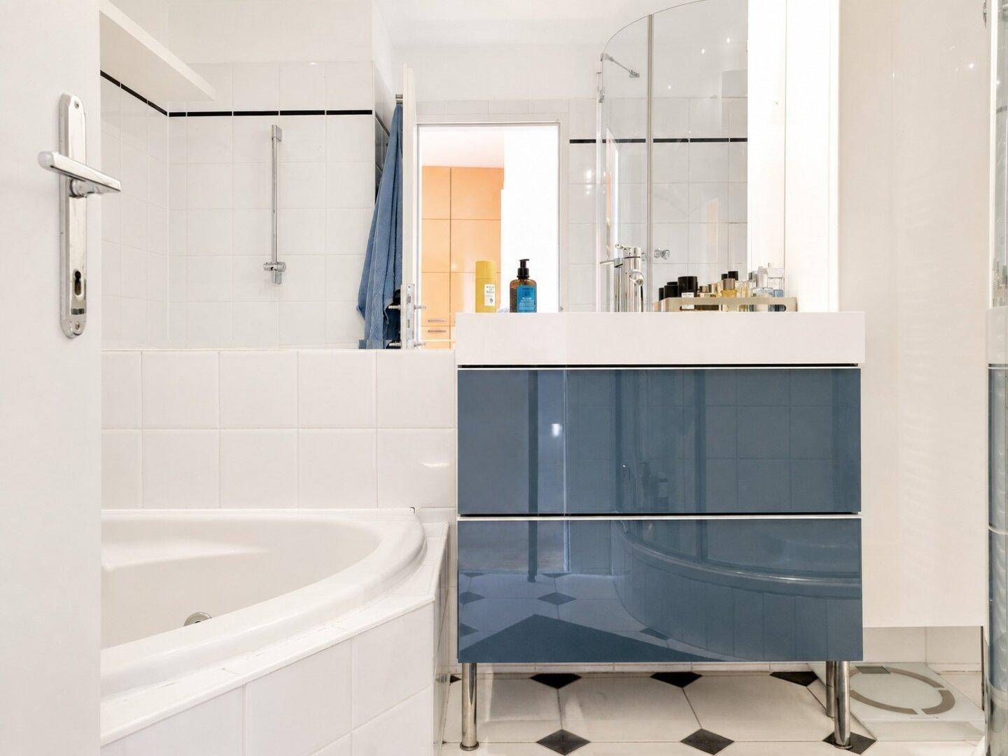 Modernes Badezimmer mit Eckbadewanne, stilvollem blauen Waschtisch und separater Duschkabine.