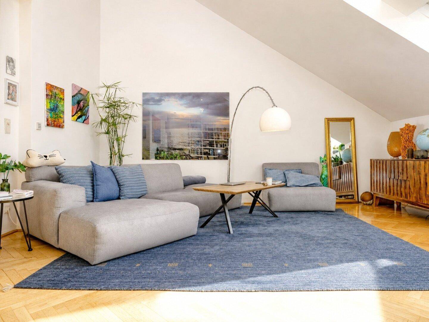 Geräumiges Wohnzimmer mit bequemer Couch, Couchtisch und moderner Kunst an den hellen Wänden.