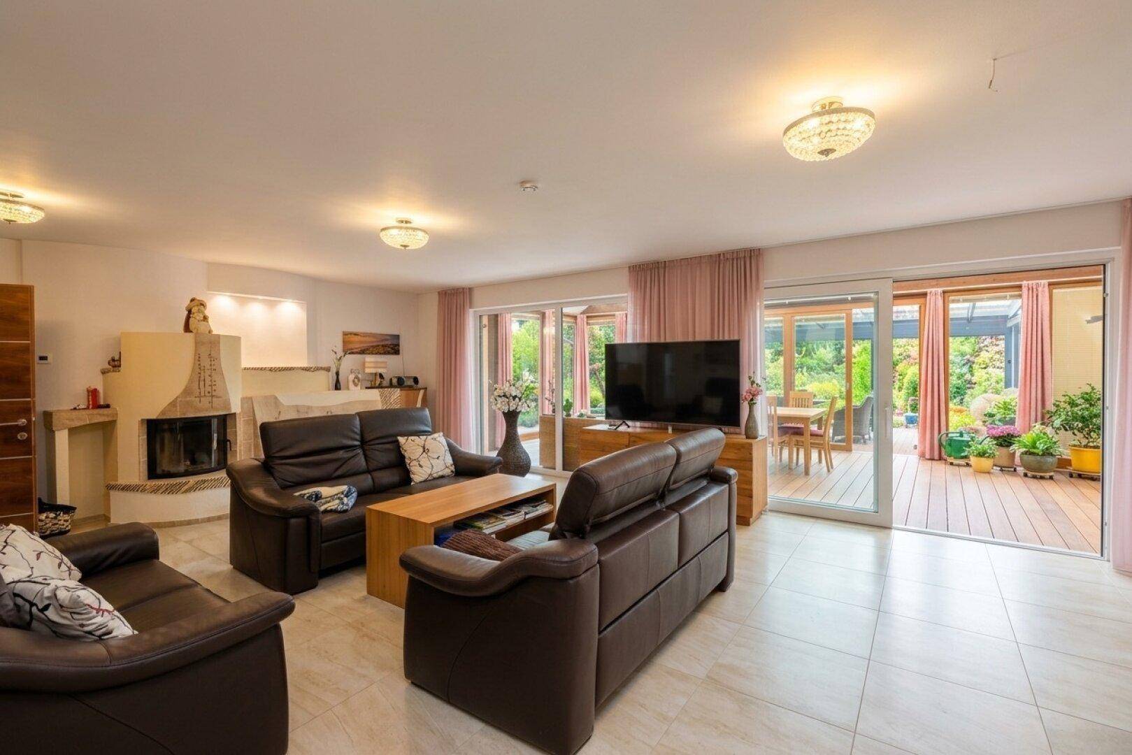 Gemütliches Wohnzimmer mit Kamin, Ledersofas und direktem Zugang zur Holzterrasse.
