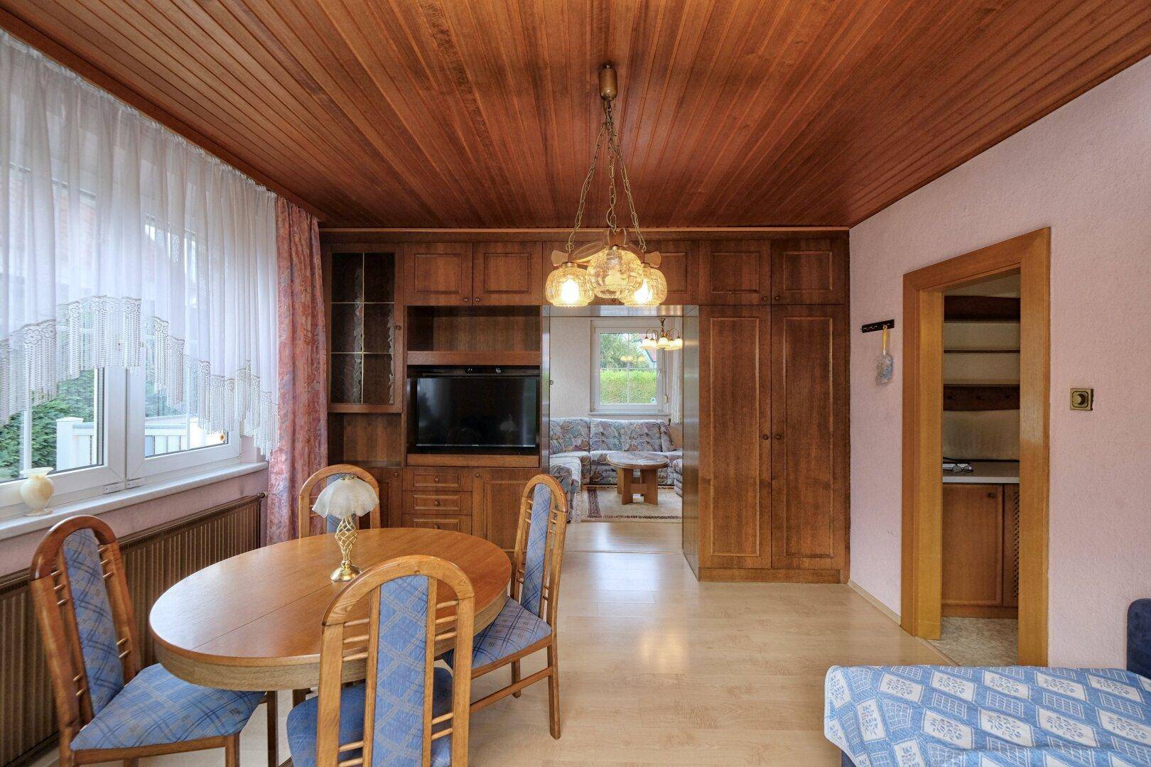 Gemütlicher Essbereich mit Holztäfelung an der Decke und Blick in das angrenzende Wohnzimmer.