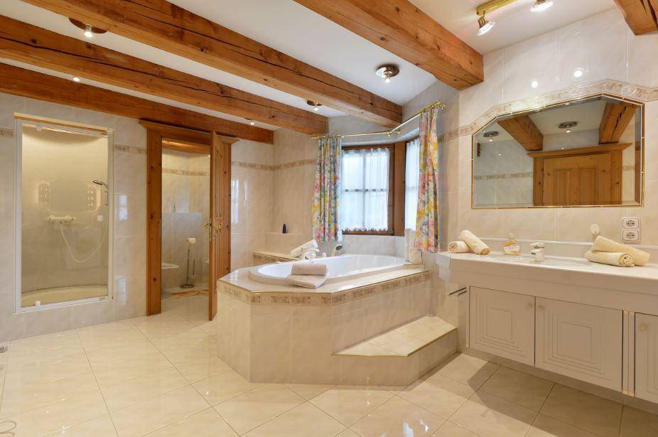 Großes Badezimmer mit Eckbadewanne, separater Dusche und Holzbalkendecke.