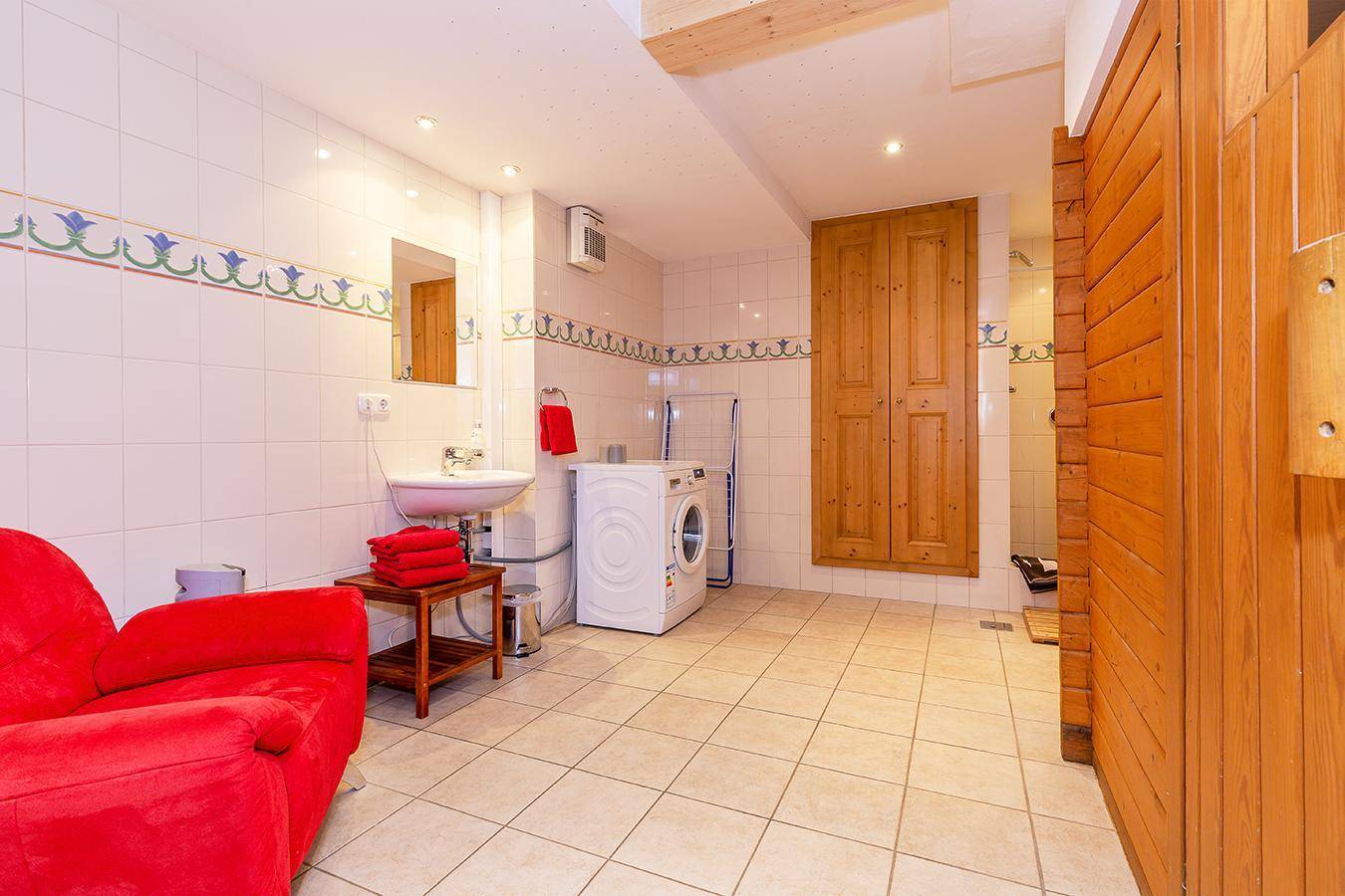 Praktischer Hauswirtschaftsraum mit Waschmaschine, Waschbecken und Zugang zur Sauna.
