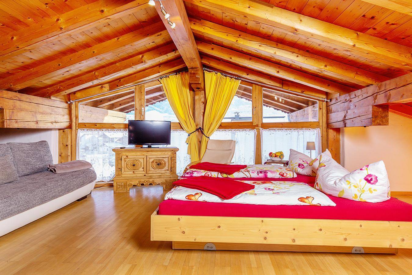 Gemütliches Schlafzimmer im Dachgeschoss mit Holzbalken, Doppelbett und Bergblick.