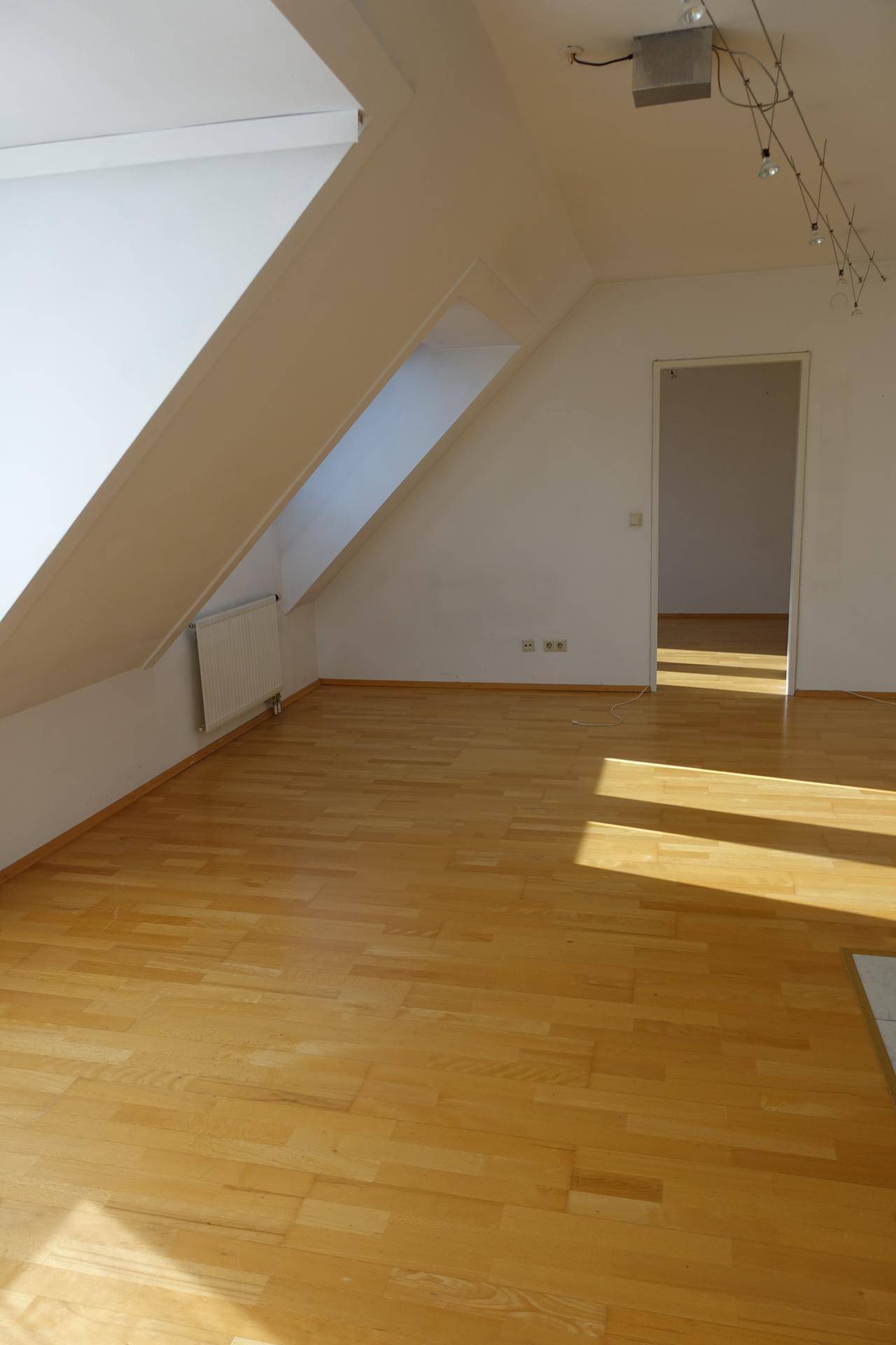 Geräumiges Dachgeschosszimmer mit Holzboden und schrägen Wänden, ideal für individuelle Gestaltung.