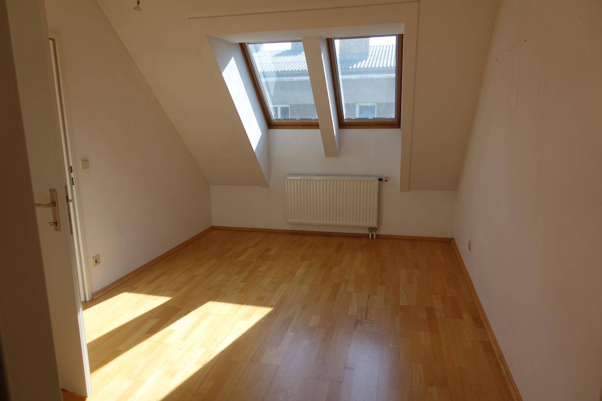 Gemütliches Schlafzimmer im Dachgeschoss mit Holzboden und zwei Dachfenstern für viel Licht.