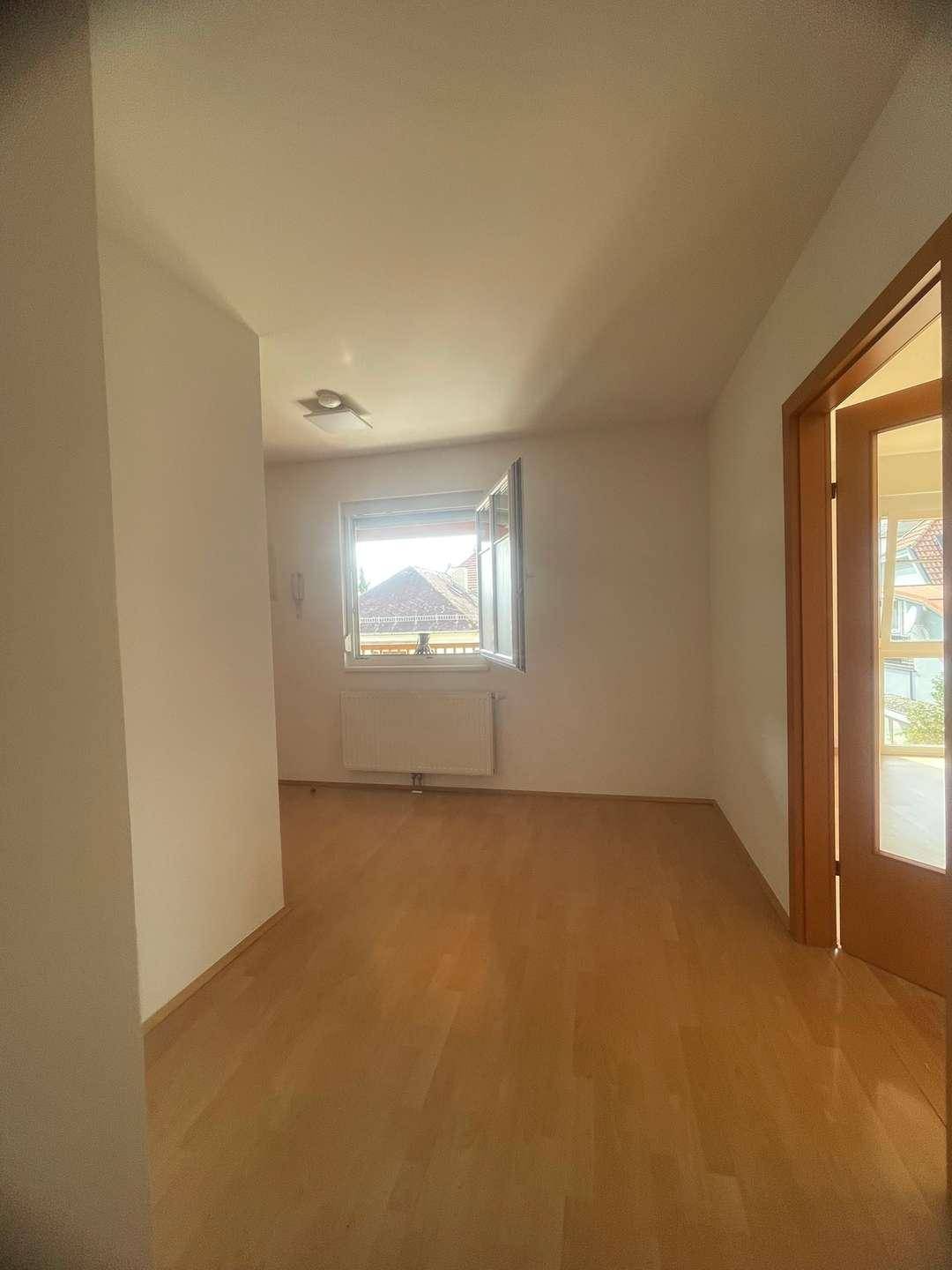 Helles Zimmer mit Holzboden und Fenster, das einen Blick auf die Umgebung bietet.
