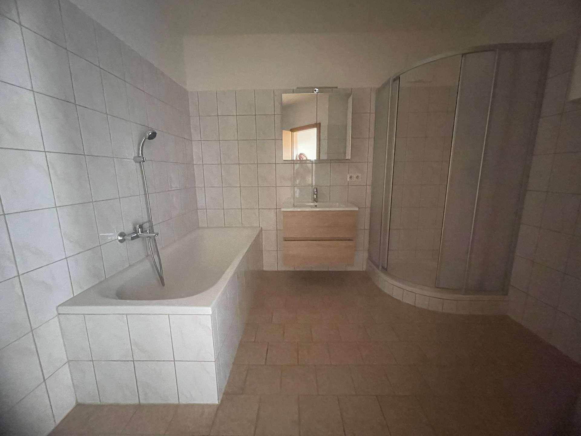 Gefliestes Badezimmer mit Badewanne, Duschkabine und Waschbecken mit Spiegelschrank.
