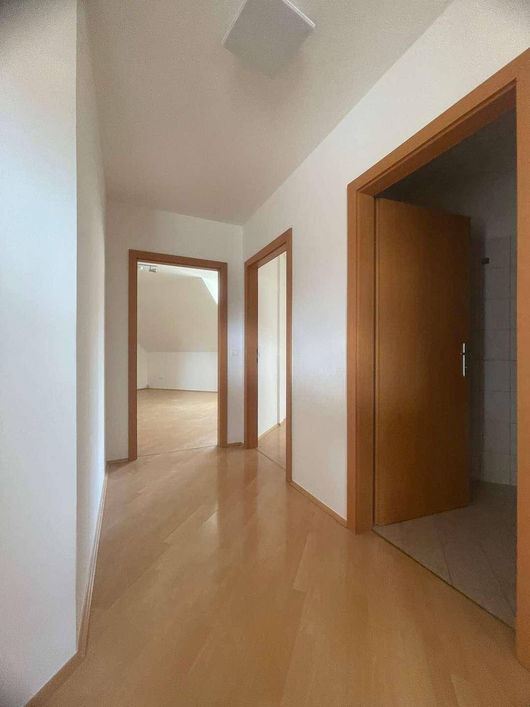 Heller Flur mit Holzboden und mehreren Türen zu den angrenzenden Zimmern.