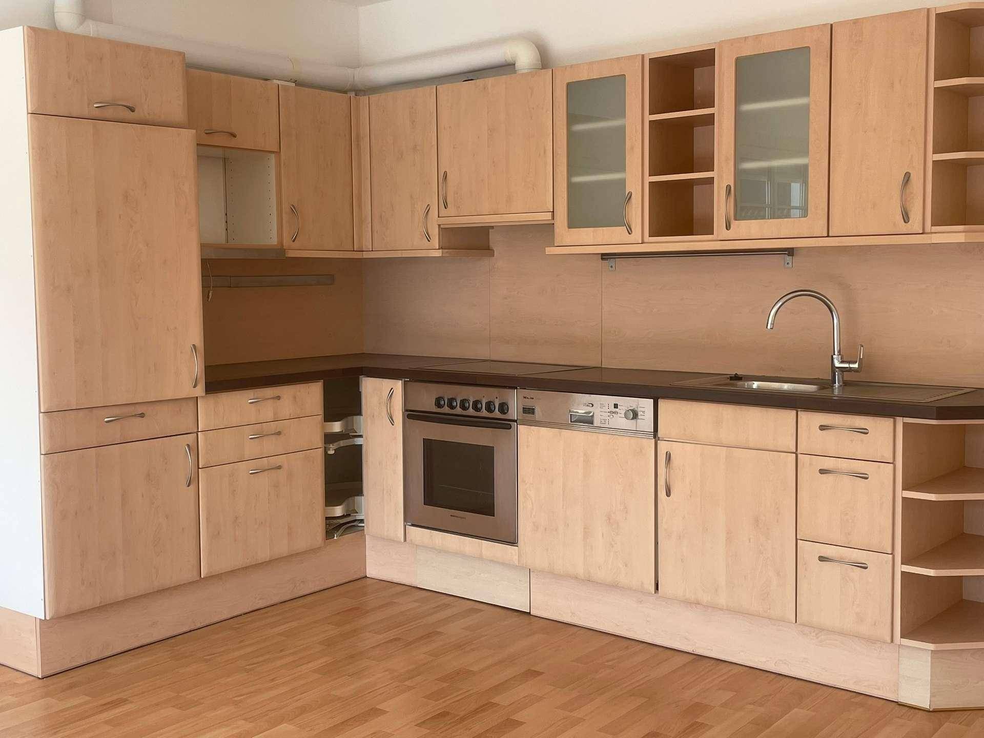 Funktionale Einbauküche mit hellen Holzfronten, integrierten Geräten und Spülbecken.