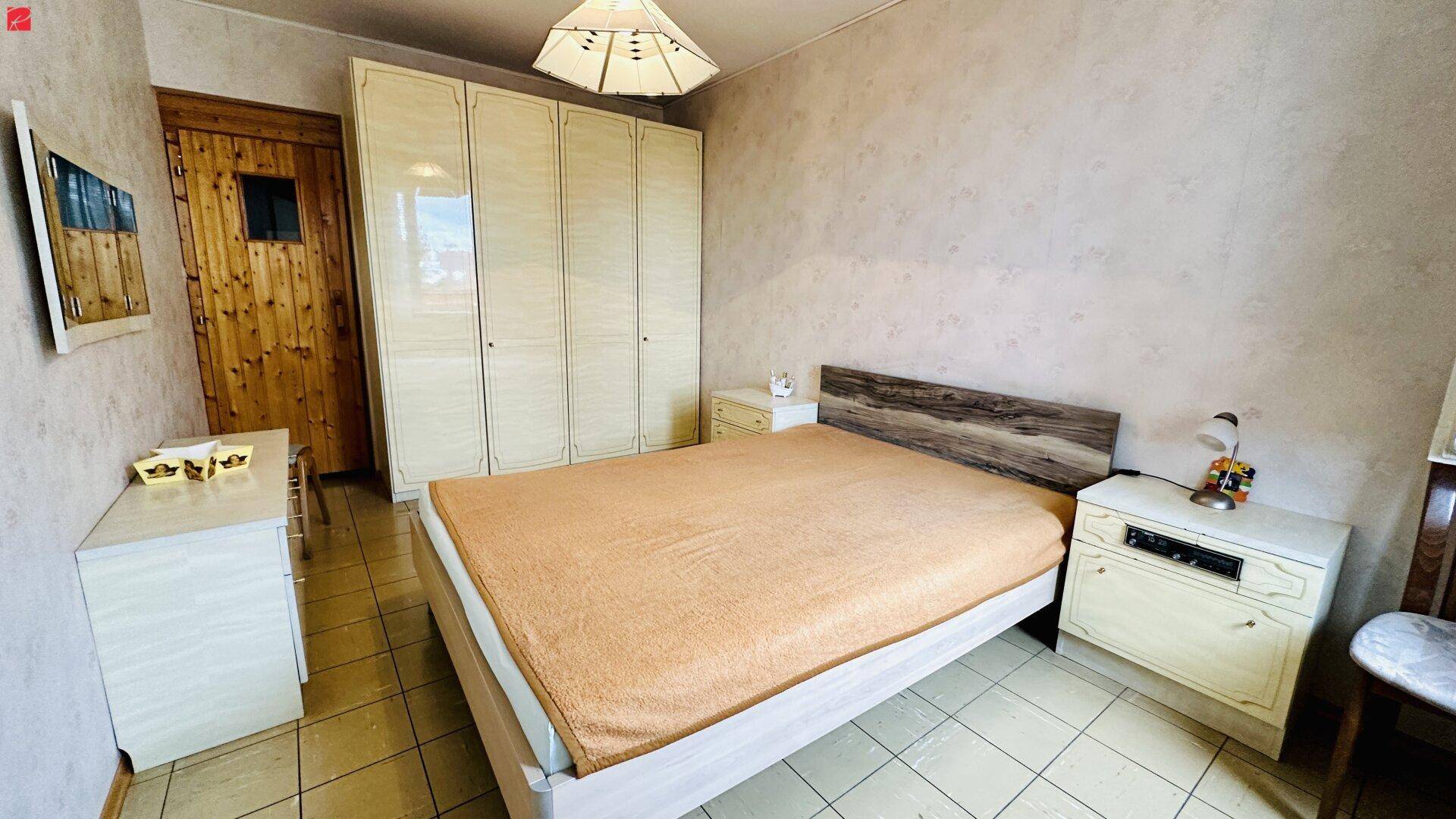 Schlafzimmer mit Doppelbett, Einbauschränken und Fliesenboden.