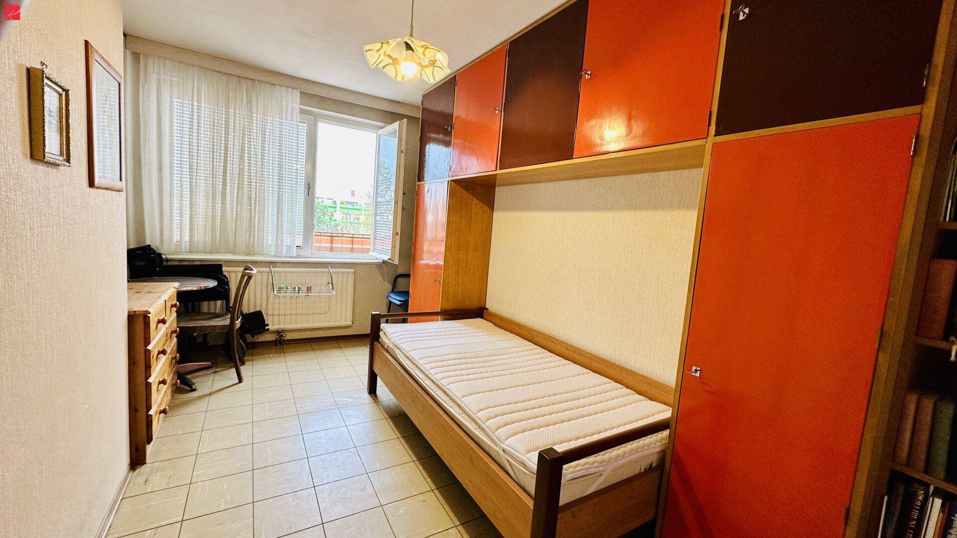 Helles Zimmer mit Einzelbett, Schreibtisch und integrierten Schränken.