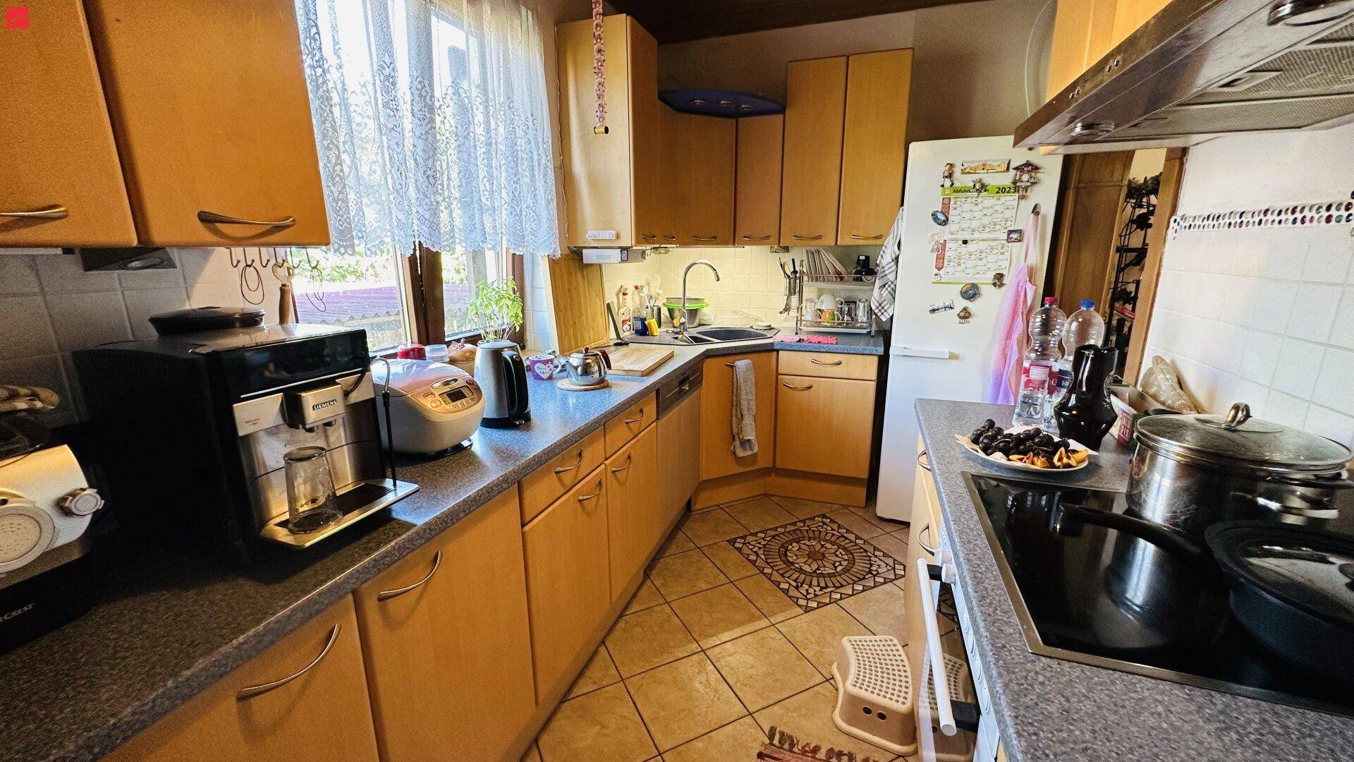 Funktionale Küche mit hellen Holzschränken, dunkler Arbeitsplatte und Fenster.