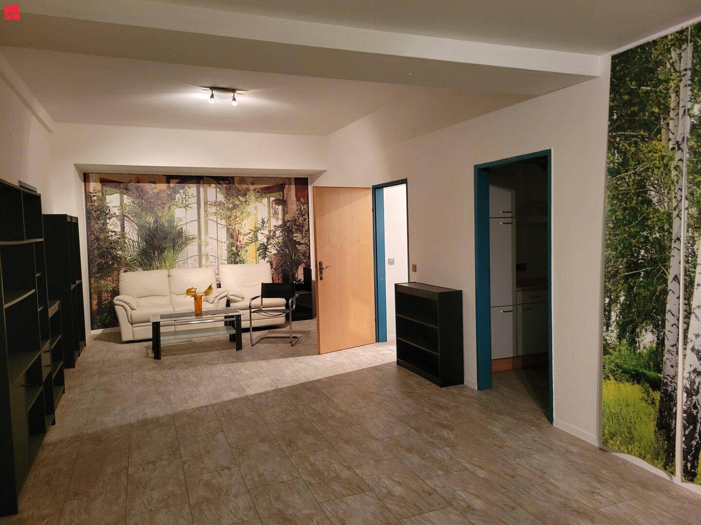 Geräumiges Wohnzimmer mit Fliesenboden, einem hellen Sofa und dekorativer Waldtapete an den Wänden.