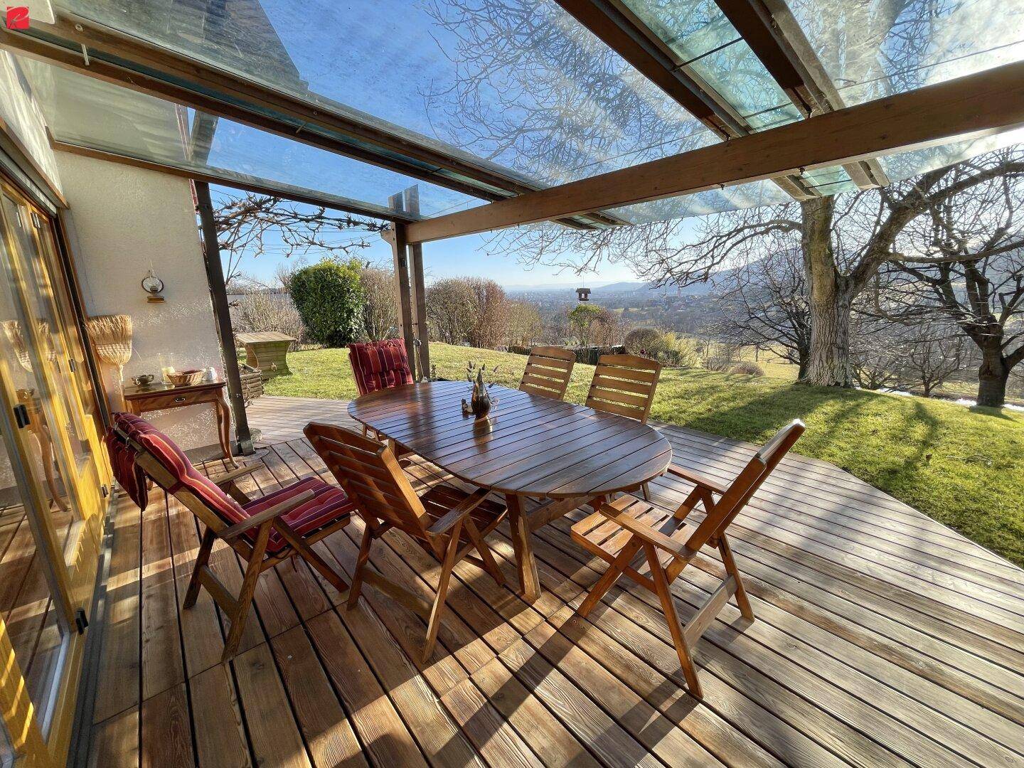 Überdachte Holzterrasse mit Esstisch und Stühlen, ideal für Mahlzeiten im Freien mit Weitblick.