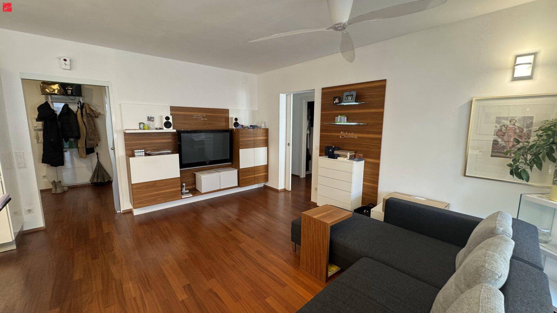 Helles Wohnzimmer mit dunklem Holzboden, modernem Sofa und Medieneinheit aus Holz.