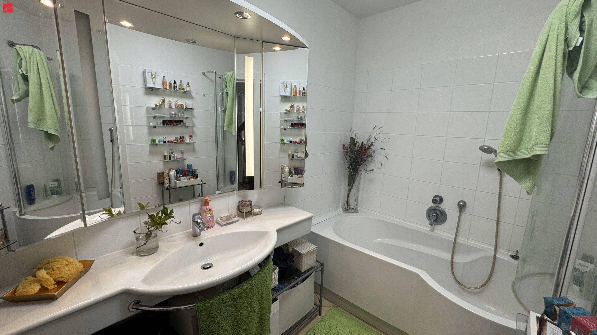 Helles Badezimmer mit Badewanne, Dusche, Einzelwaschbecken und großem Spiegelschrank.