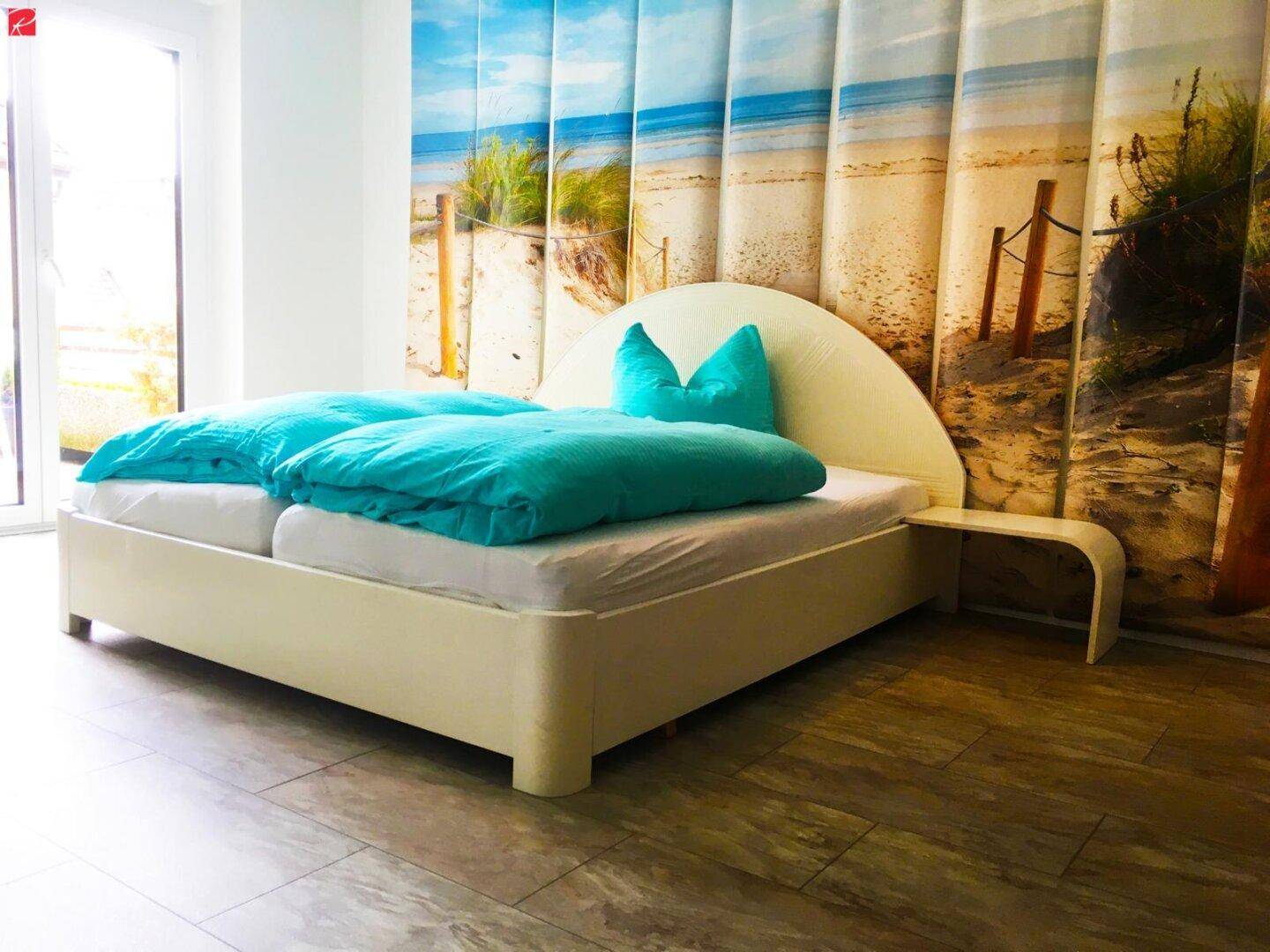 Helles Schlafzimmer mit Doppelbett, Holzboden und dekorativer Strandtapete.