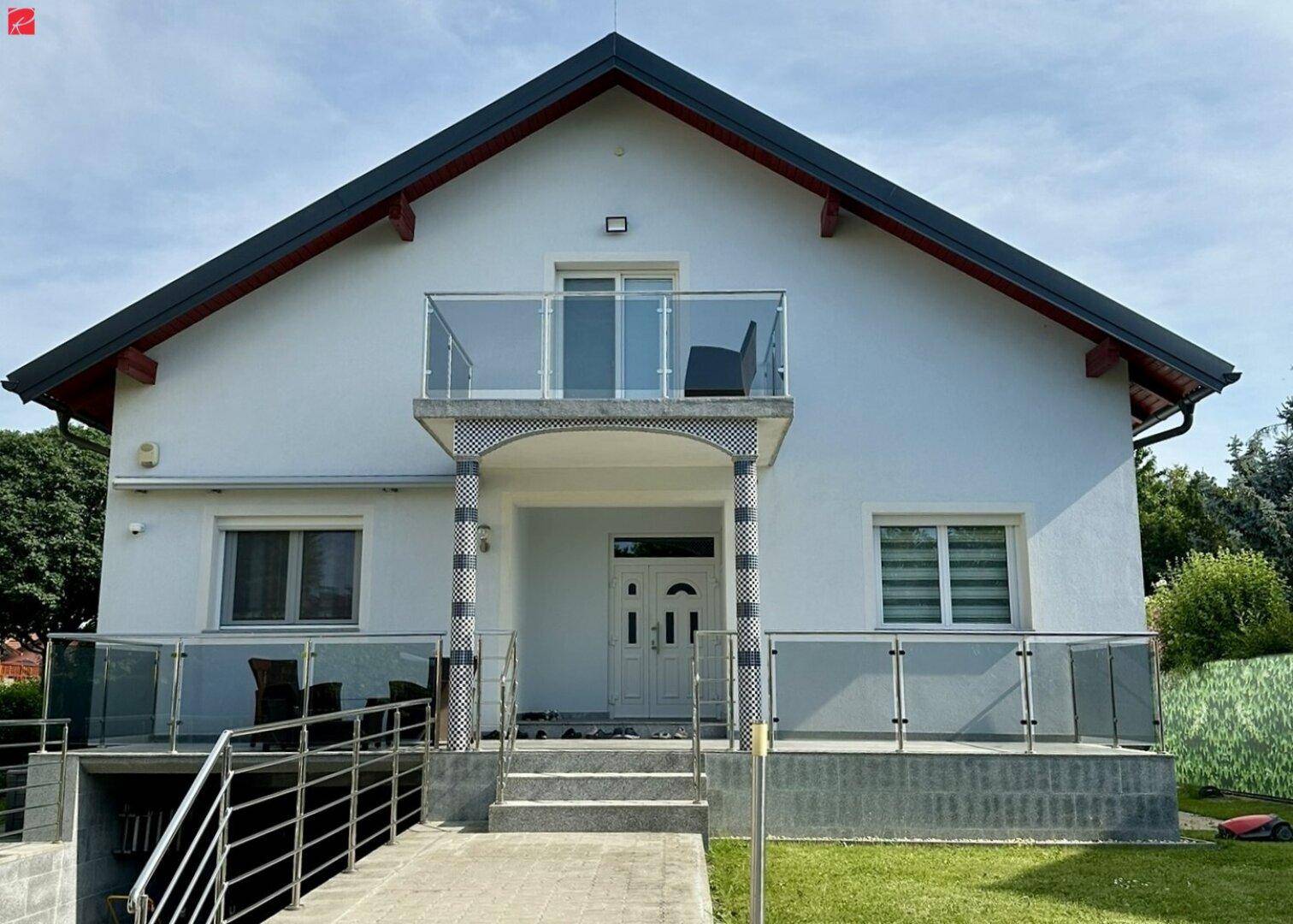 Moderne Hausfassade mit Haupteingang, kleinem Balkon und barrierefreiem Zugang zum Untergeschoss.