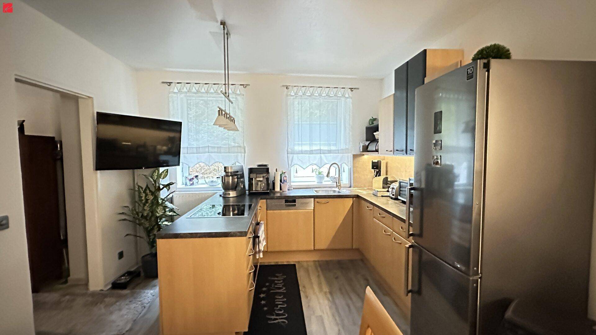 Funktionale Küche mit hellen Holzschränken, dunkler Arbeitsplatte und modernen Geräten.