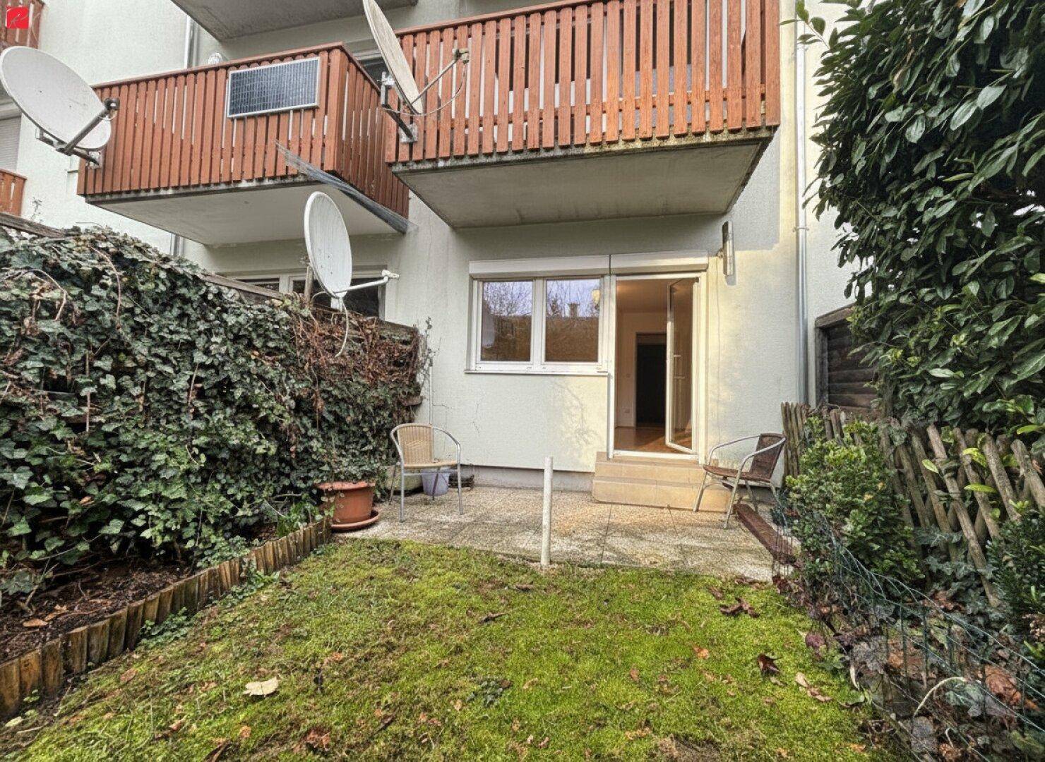Terrasse mit direktem Zugang zum Garten und Blick auf die oberen Balkone des Gebäudes.