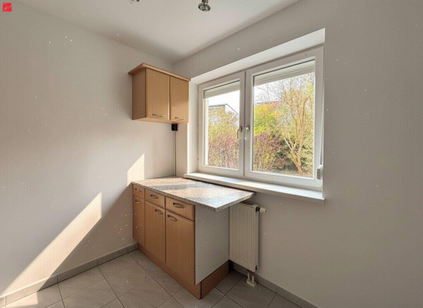 Kleiner Küchenbereich mit Unterschränken, Arbeitsplatte und Fenster, ideal für eine Kochnische.