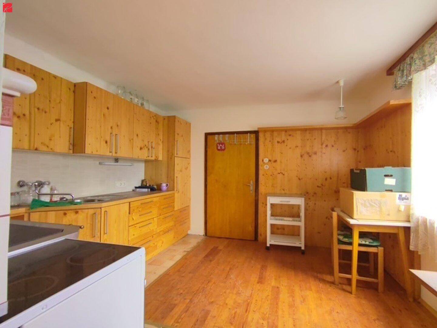 Traditionelle Küche mit hellen Holzschränken, integrierten Geräten und einem Holzboden, der Wärme ausstrahlt.