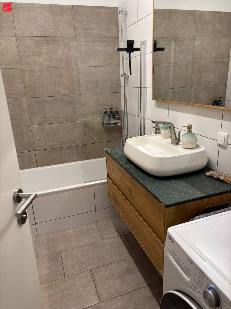 Helles Badezimmer mit Badewanne, Duschabtrennung und modernem Waschtisch.
