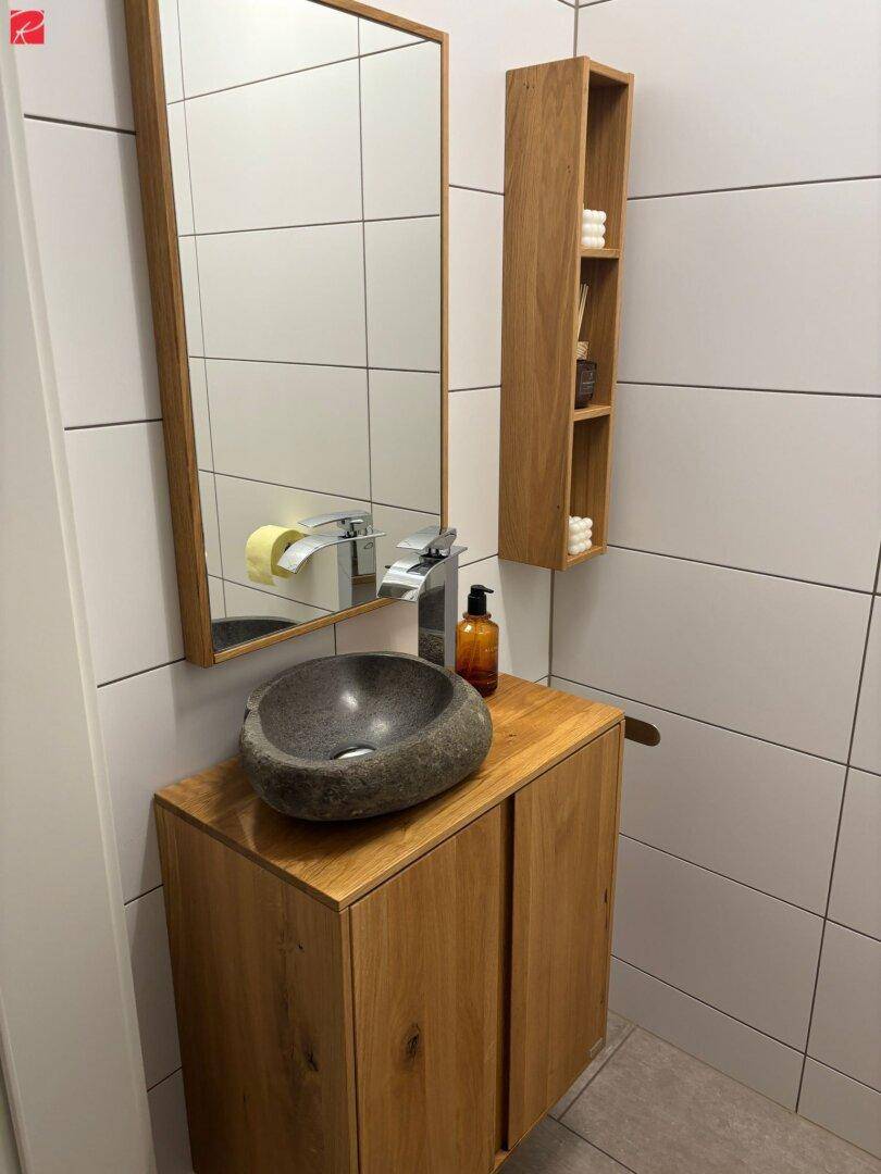 Stilvolles Gäste-WC mit Natursteinwaschbecken und Holzunterschrank.