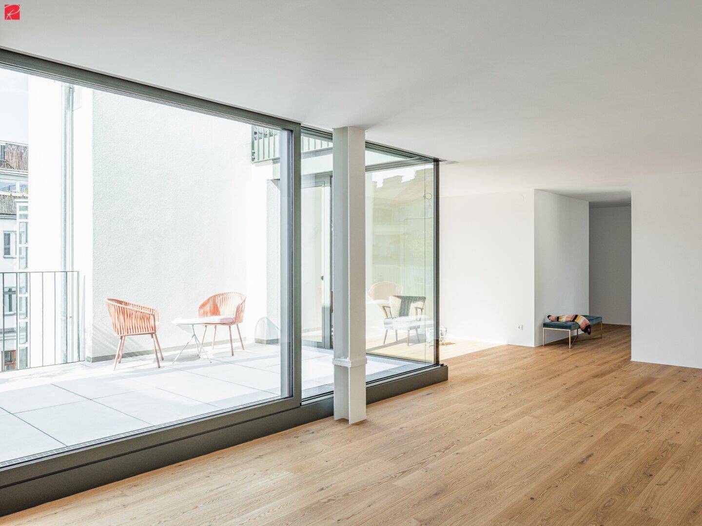 Lichtdurchfluteter Wohnbereich mit Eichenparkettboden und raumhohen Fenstern zum Balkon.