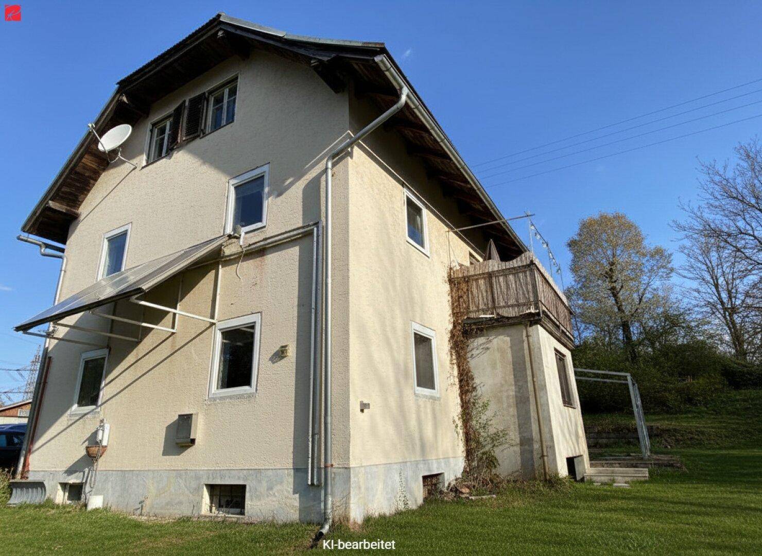 Rückseite des Hauses mit einem kleinen Holzbalkon und Blick auf die grüne Umgebung.