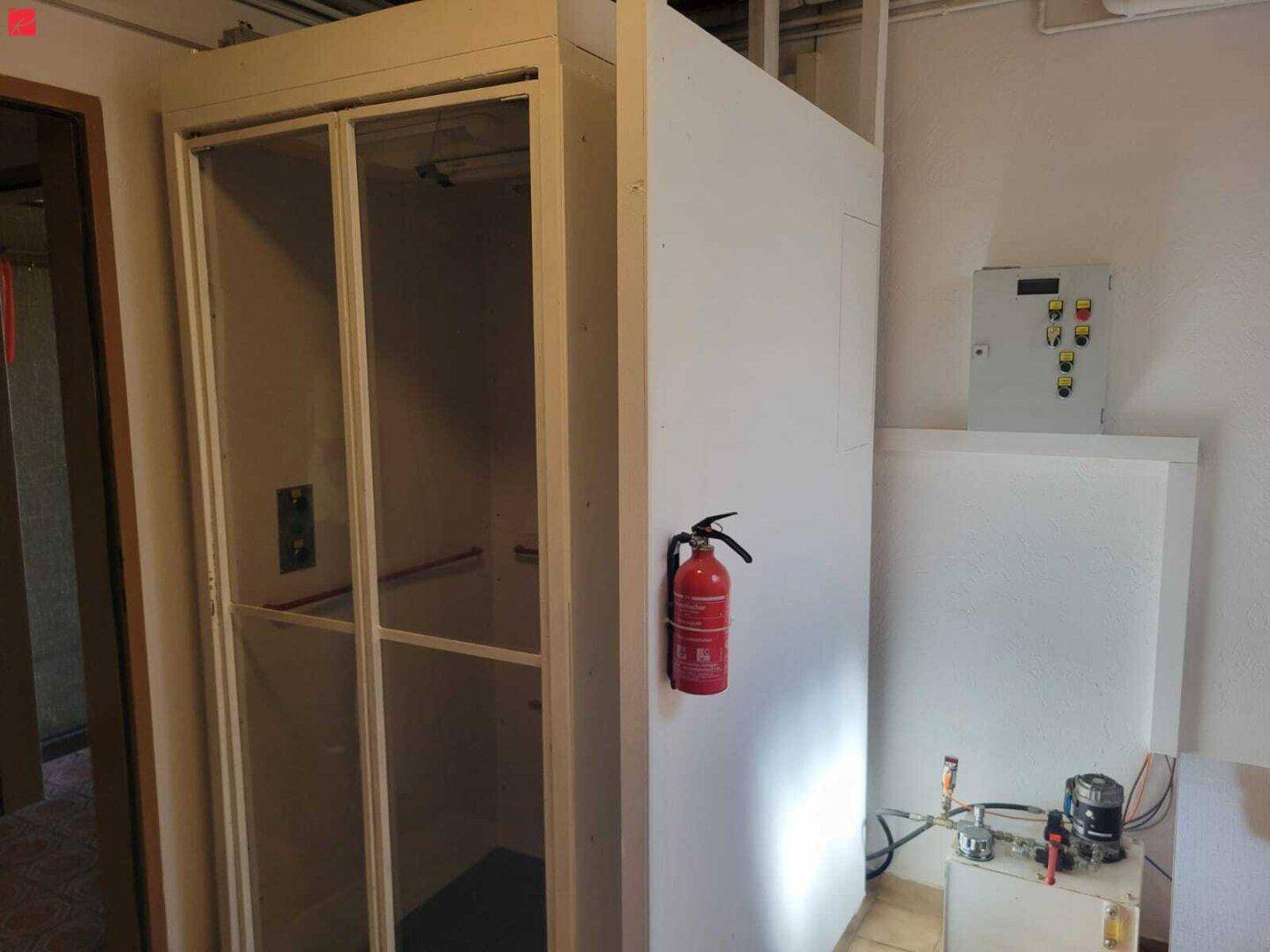 Flur oder Technikraum mit einem Personenaufzug und Brandschutzvorrichtungen.