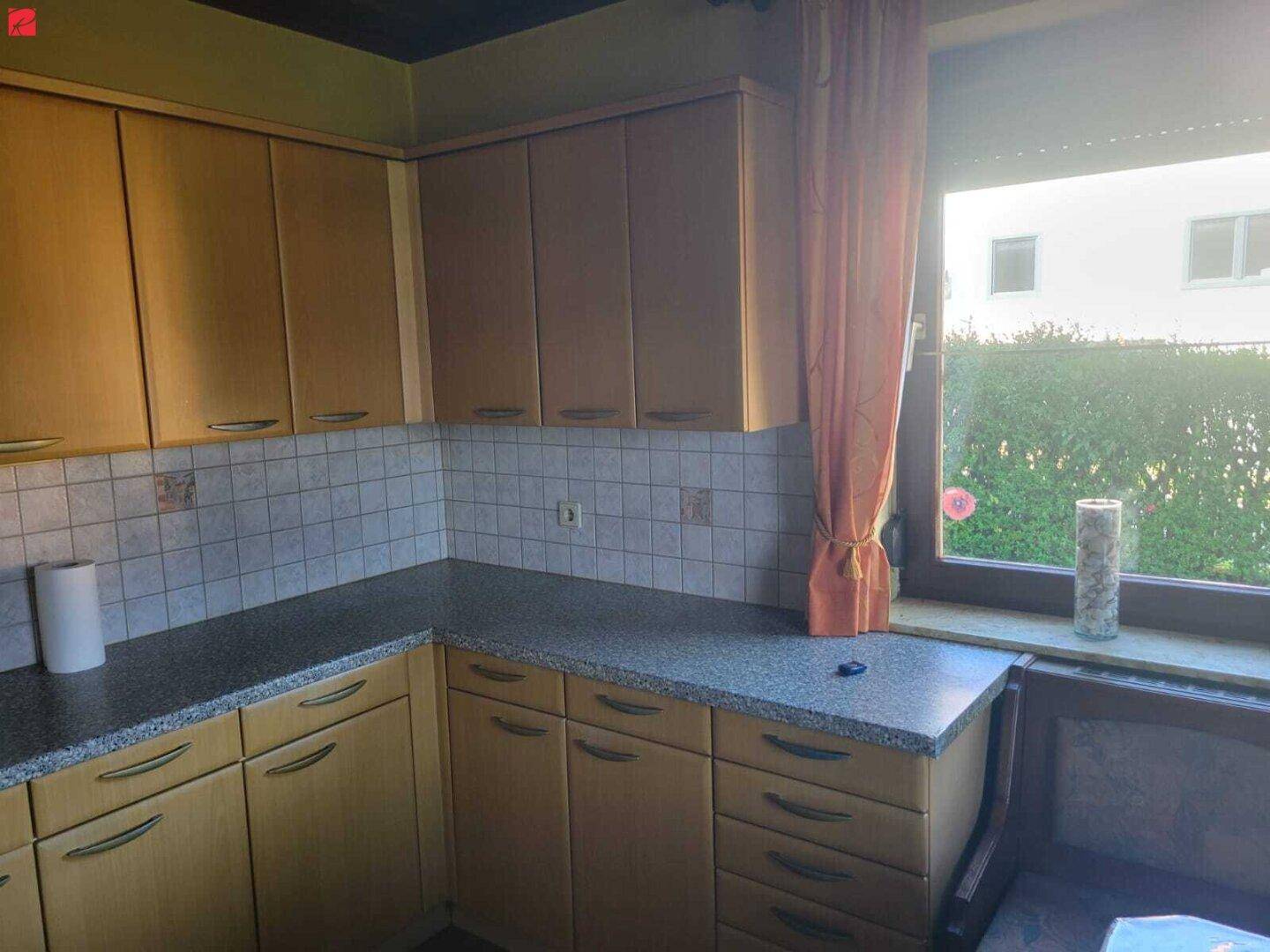 Helle Küche mit Ecklösung, Holzfronten und Fenster mit Blick ins Grüne.
