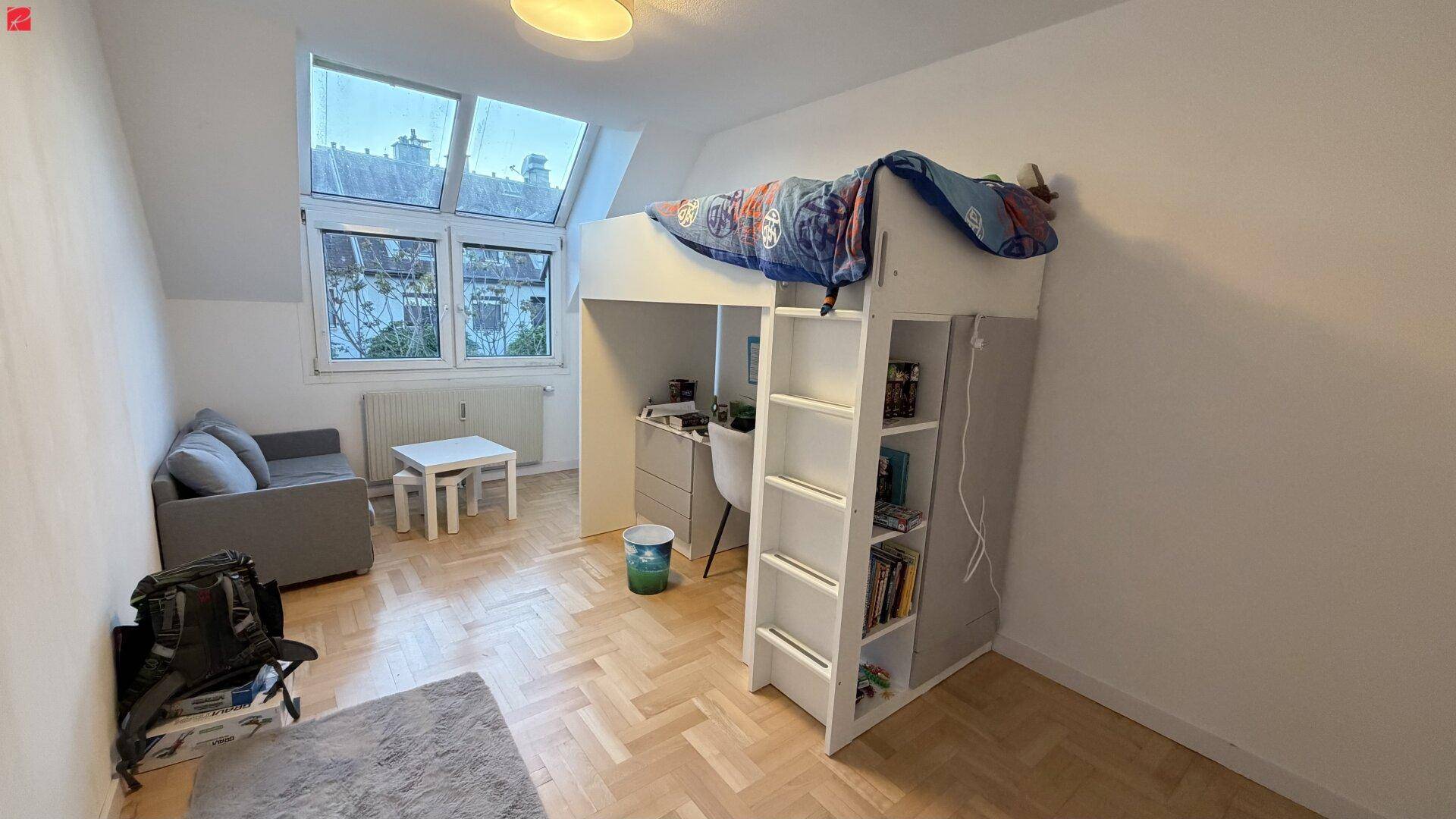 Helles Schlafzimmer mit Hochbett, Schreibtisch und Dachfenstern, ideal für Kinder oder Jugendliche.