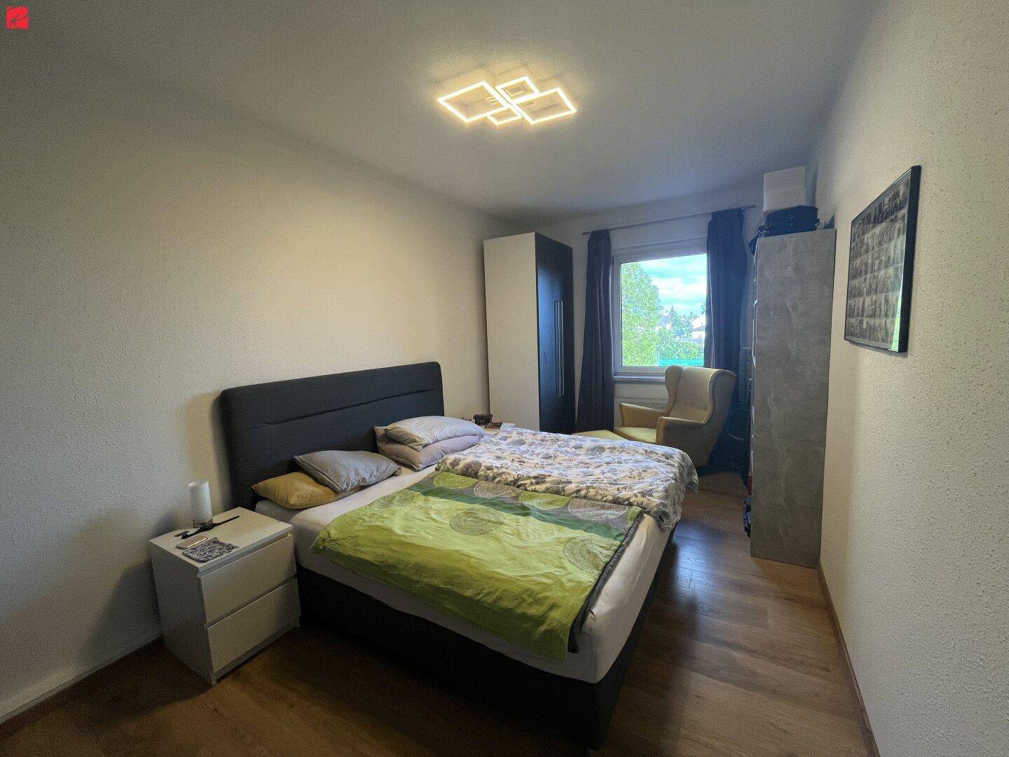 Gemütliches Schlafzimmer mit Doppelbett, Nachttischen und Kleiderschrank, hell durch das Fenster.