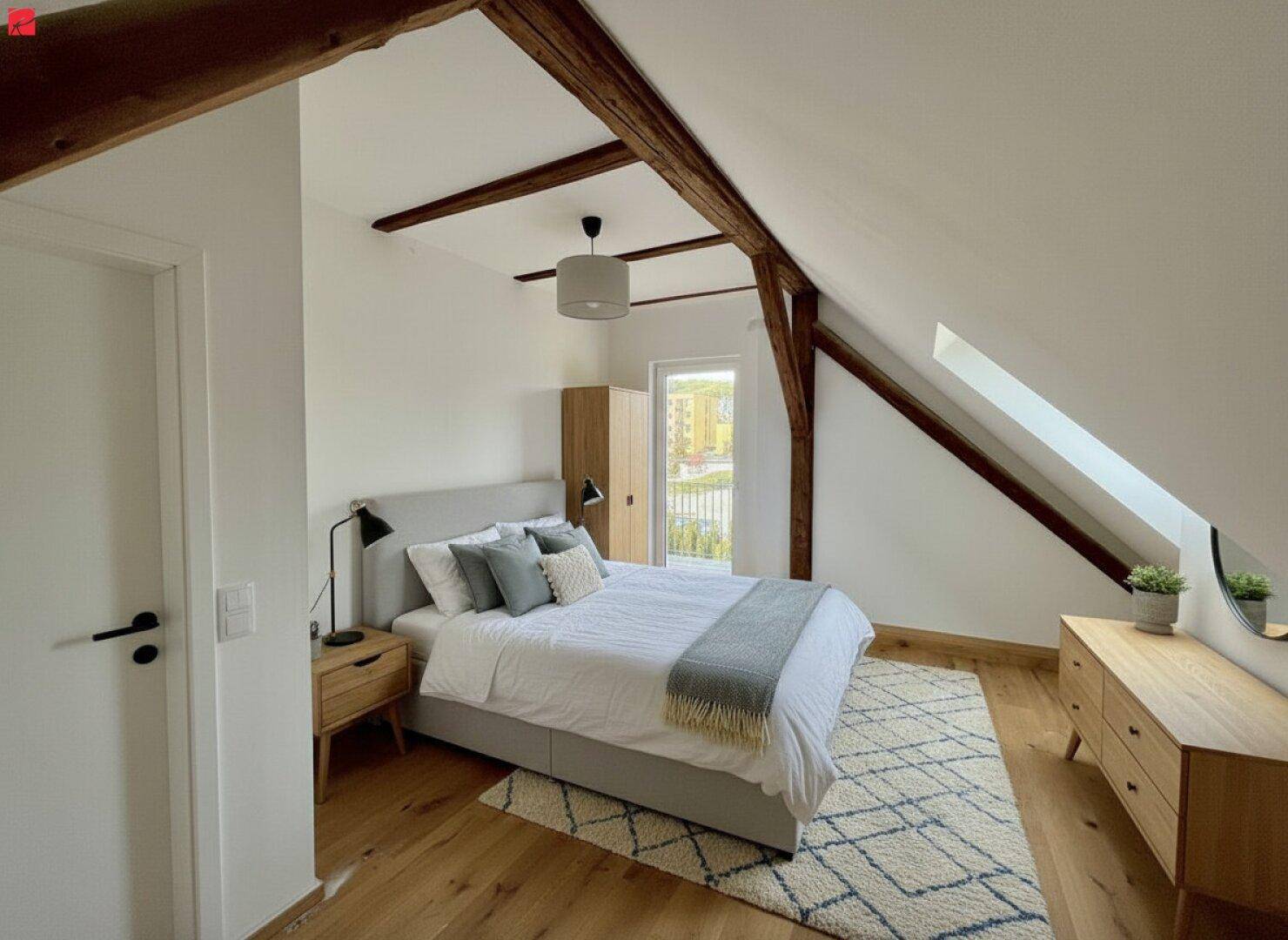 Gemütliches Schlafzimmer mit Holzbalken, Dachschräge, Holzboden und Zugang zu einem Balkon.