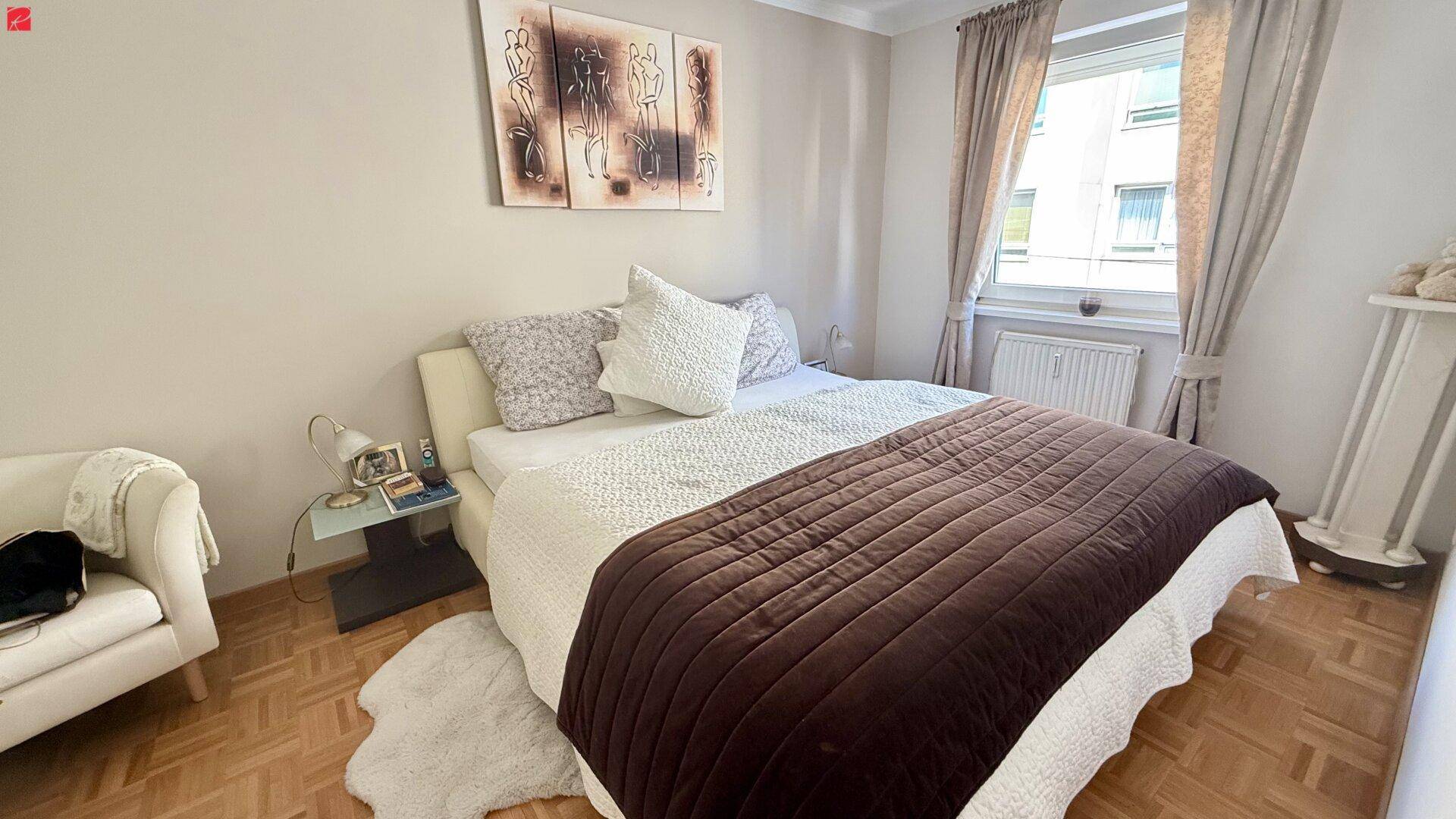 Gemütliches Schlafzimmer mit Doppelbett, Parkettboden und Fenster für natürliches Licht.