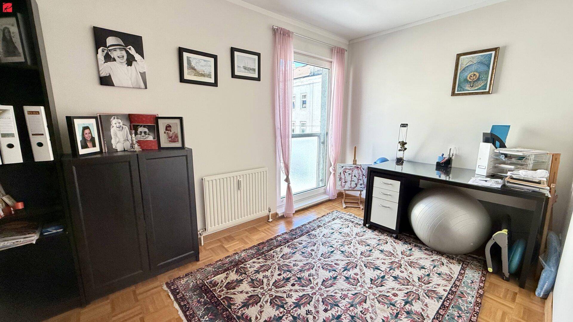 Helles Arbeitszimmer mit Parkettboden, Schreibtisch und Zugang zu einem kleinen Balkon.