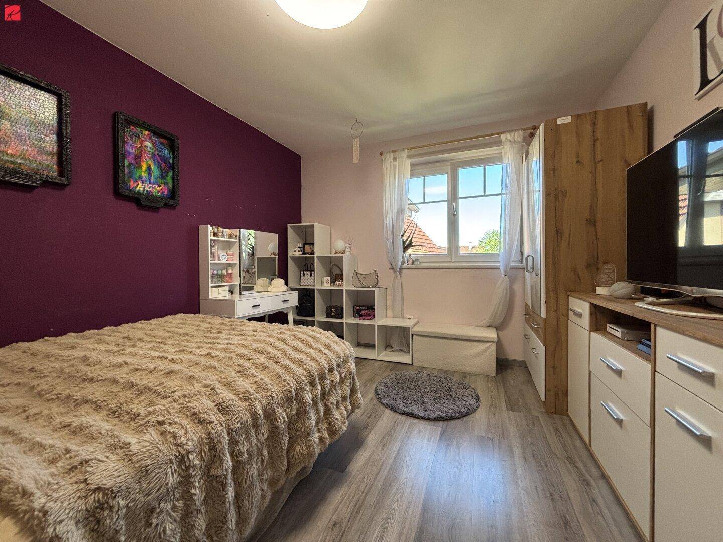 Helles Schlafzimmer mit Holzboden, Fenster und moderner Einrichtung.