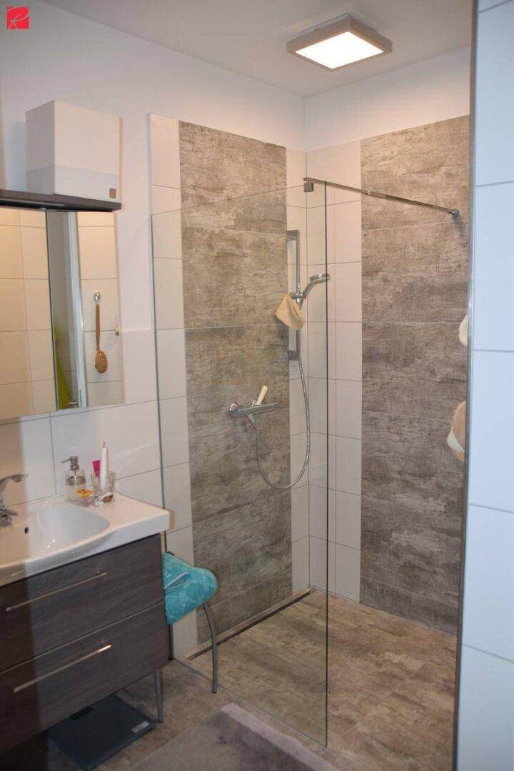 Modernes Badezimmer mit ebenerdiger Dusche, Waschtisch und großformatigen Fliesen.