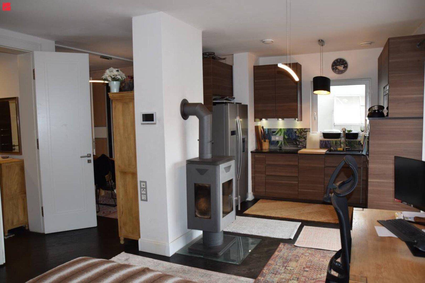 Gemütlicher offener Wohnbereich mit Holzküche, Kaminofen und Arbeitsplatz.