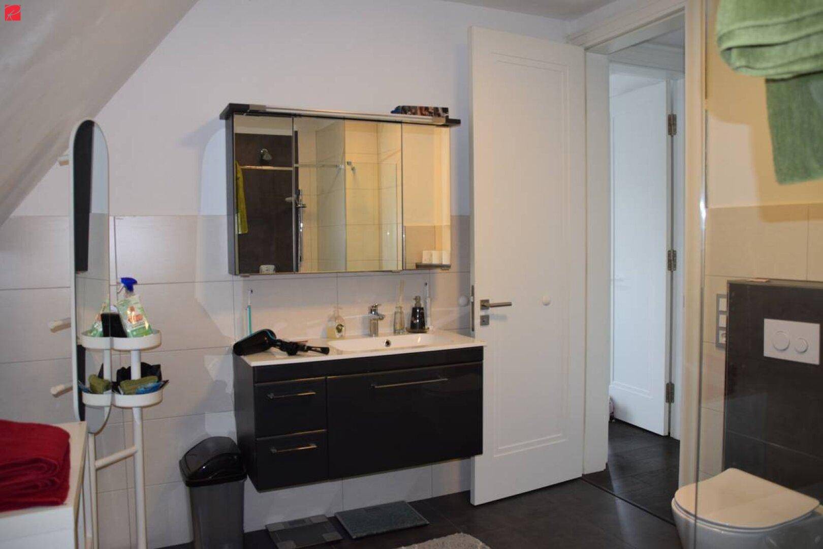 Badezimmer mit Dachschräge, Waschtisch, Spiegelschrank und Wand-WC.