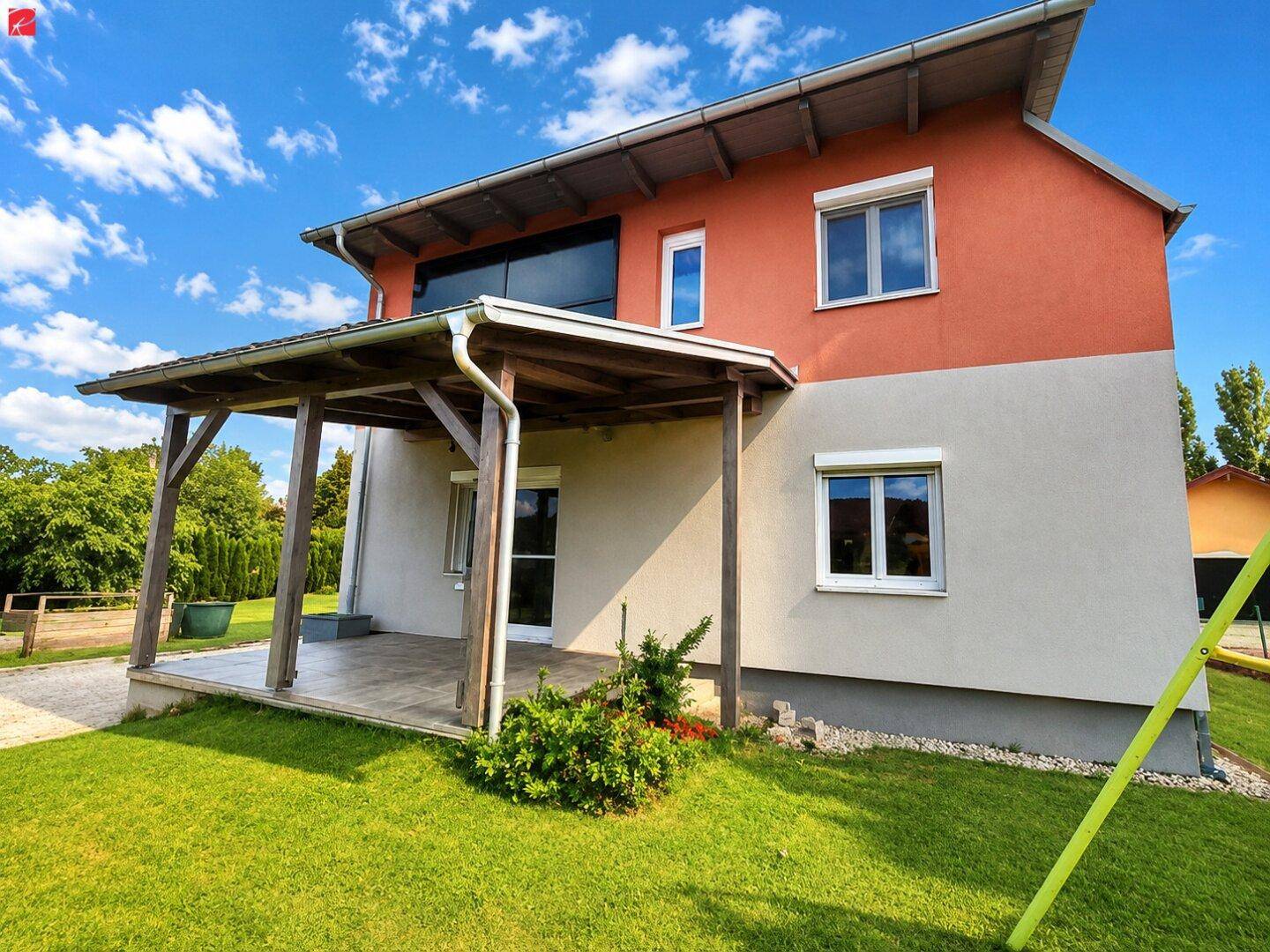 Überdachte Terrasse mit Holzbalken und Zugang zum grünen Gartenbereich.