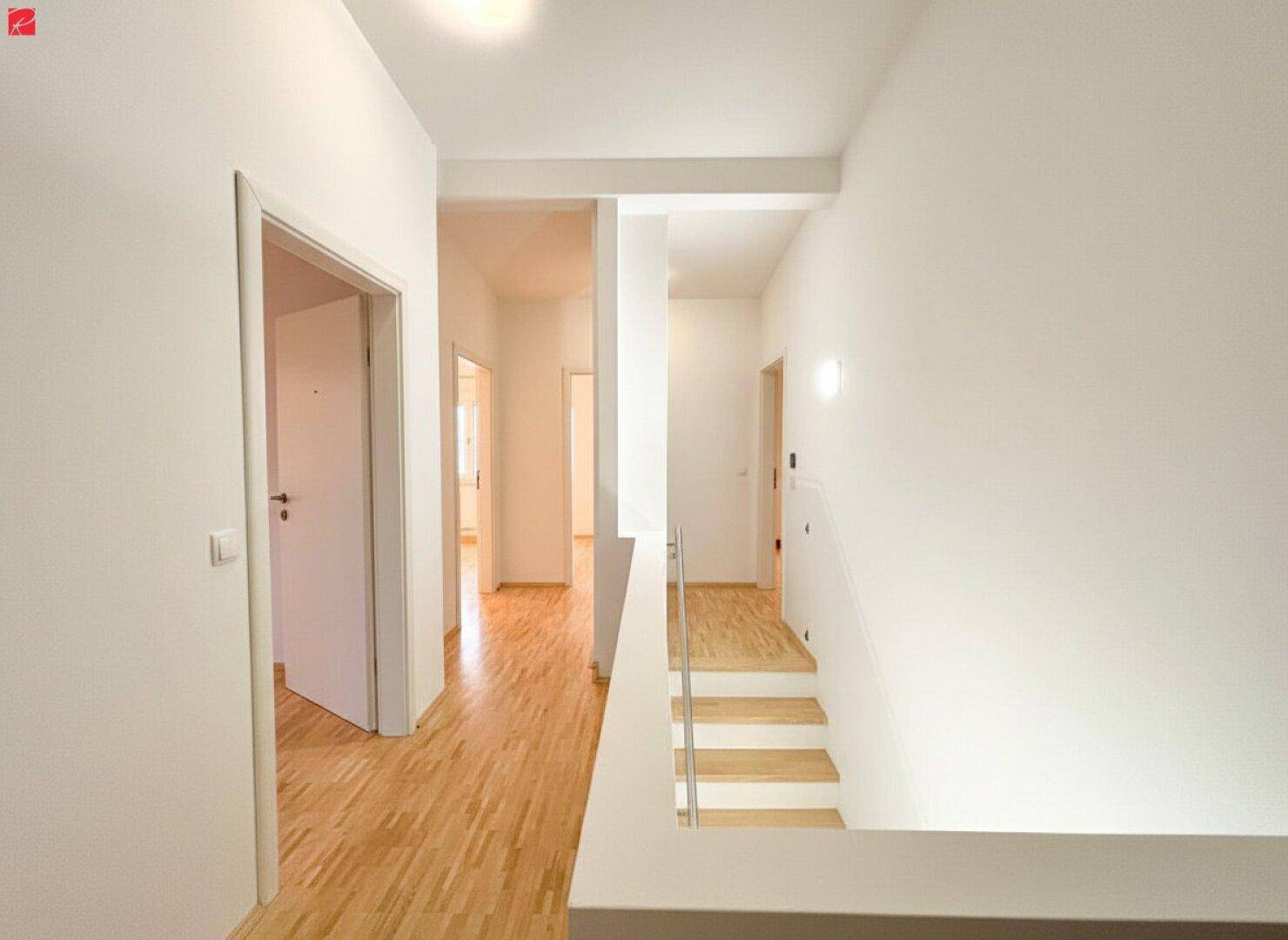 Heller Flur mit Holzfußboden und Treppenaufgang zu den oberen Etagen.