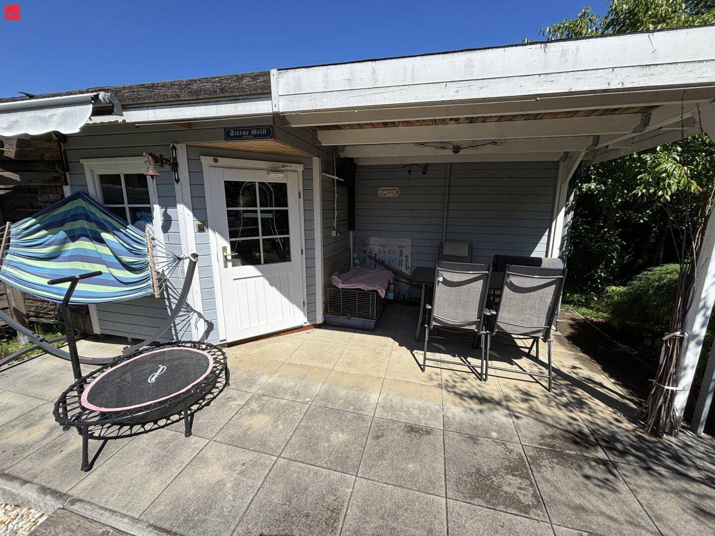 Gepflasterte Terrasse mit Gartenmöbeln und einem kleinen Trampolin.