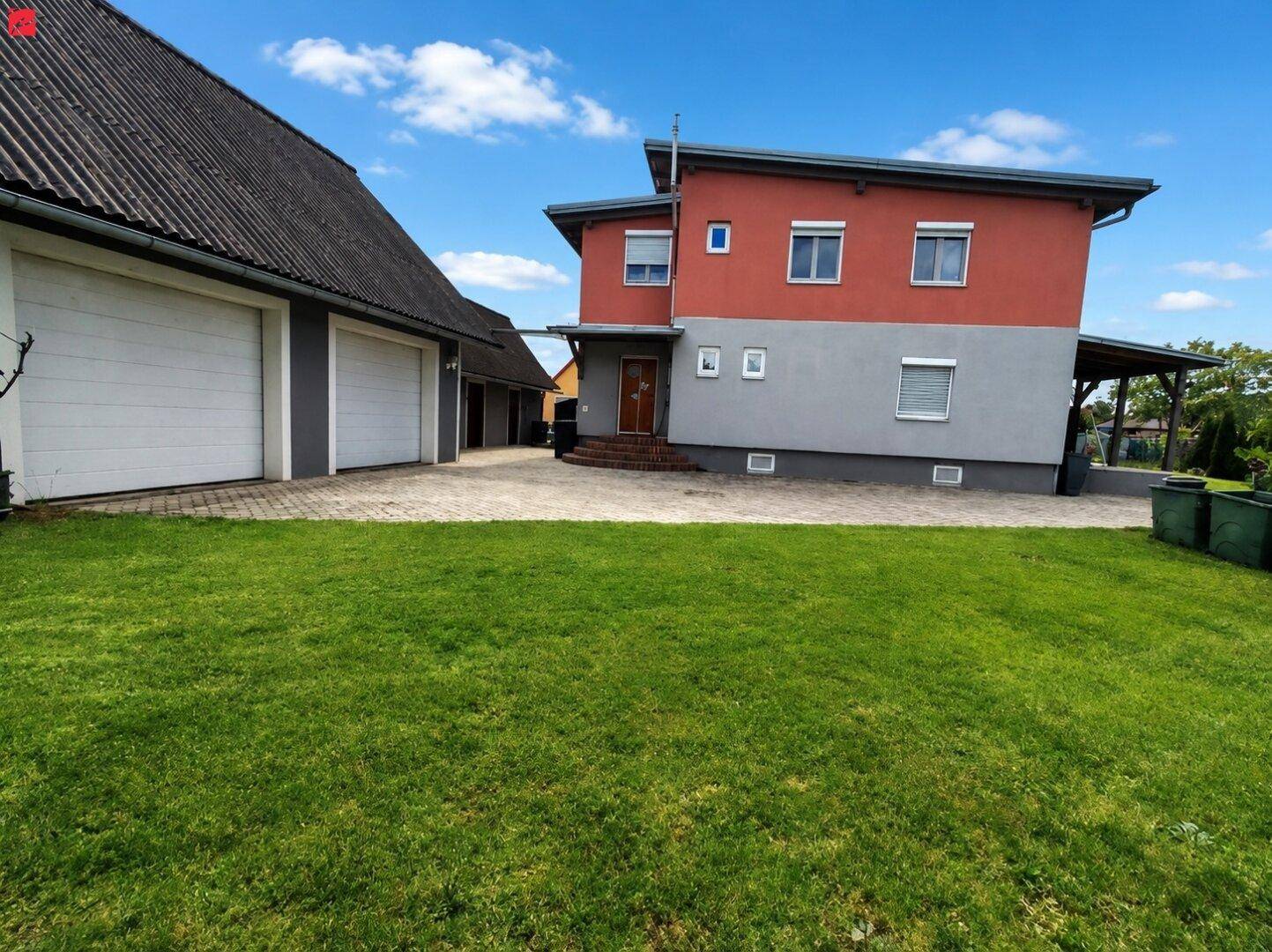 Ansicht des Hauses mit angrenzender Doppelgarage und gepflasterter Zufahrt.