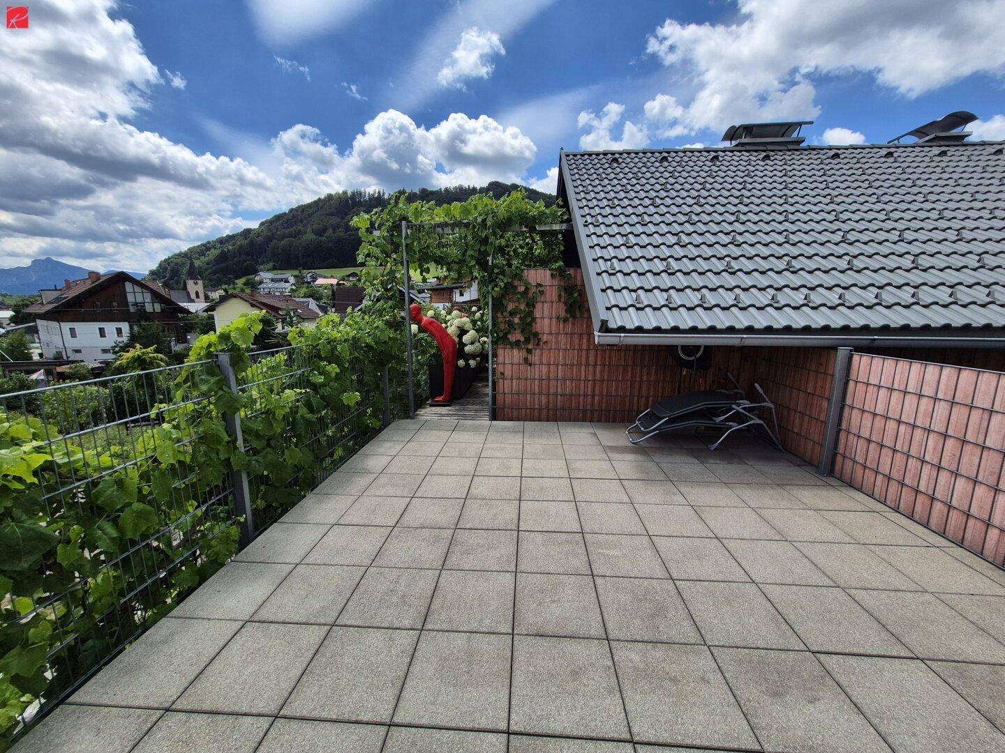 Große geflieste Terrasse mit weitem Blick über das Tal und die umliegende Berglandschaft.