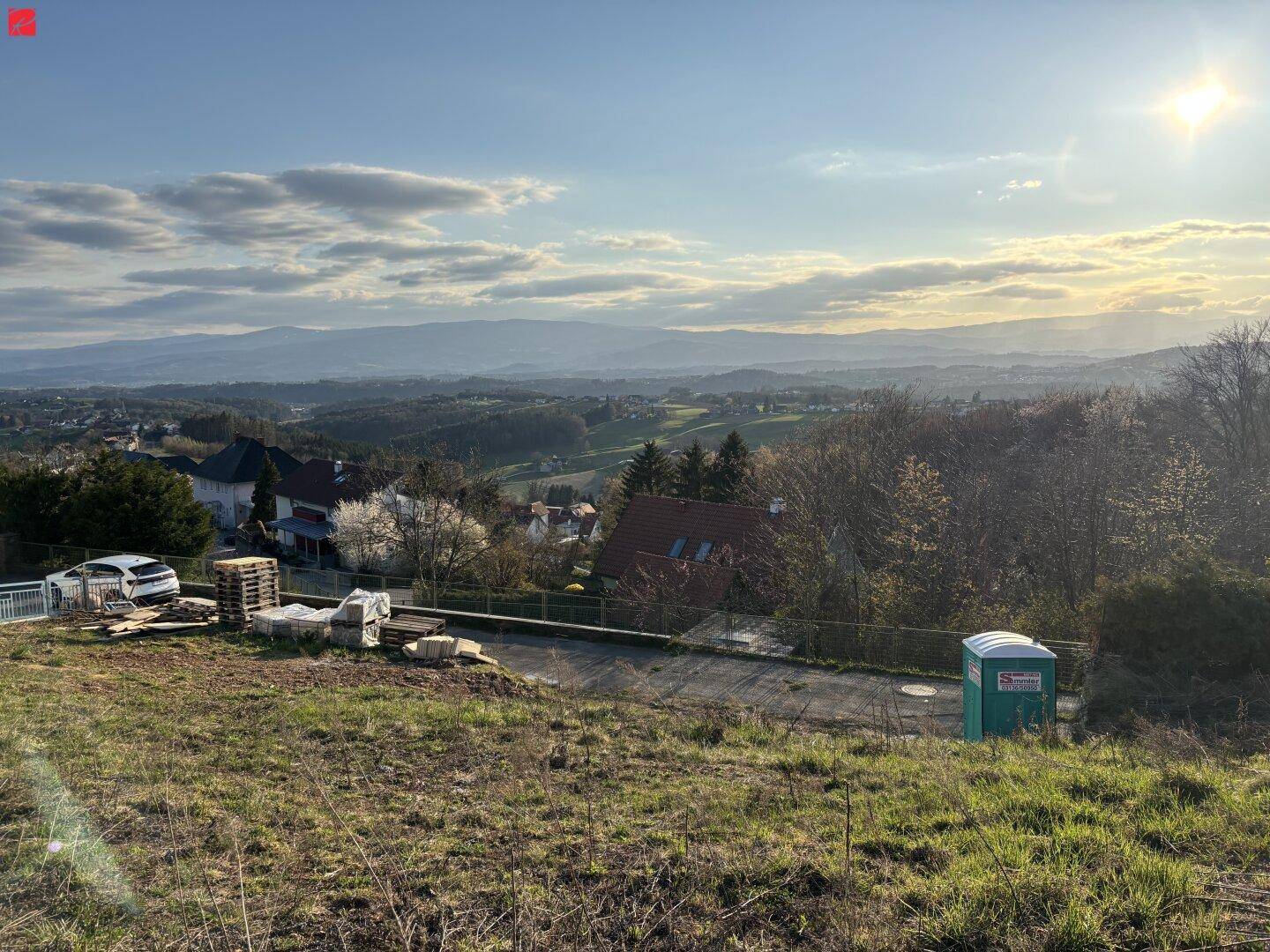 Großes, unbebautes Grundstück mit weitem Blick über die hügelige Landschaft und angrenzende Wohnbebauung.