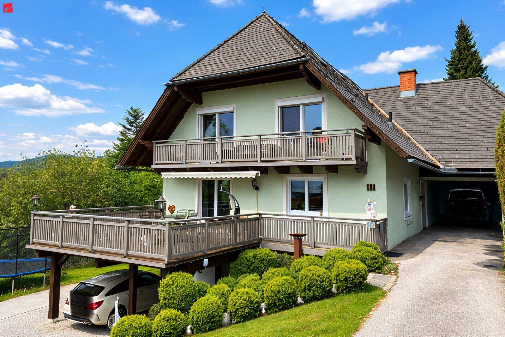 Charmantes Haus mit mehreren Balkonen, Carport und gepflegtem Gartenbereich in ländlicher Umgebung.